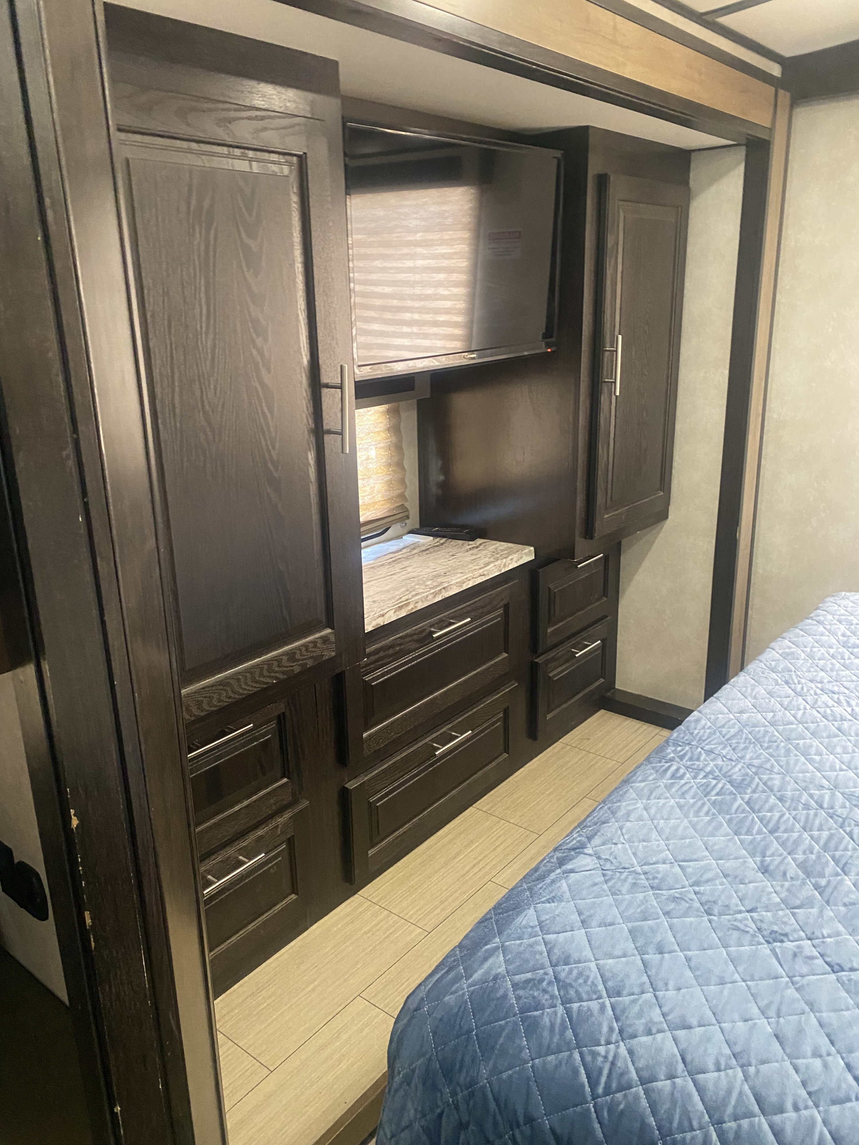 Experience comfort in this RV rental bedroom: dark wood cabinetry, integrated TV, storage drawers, and a cozy quilted bed.. FR3 FR3 Motorhome 2020