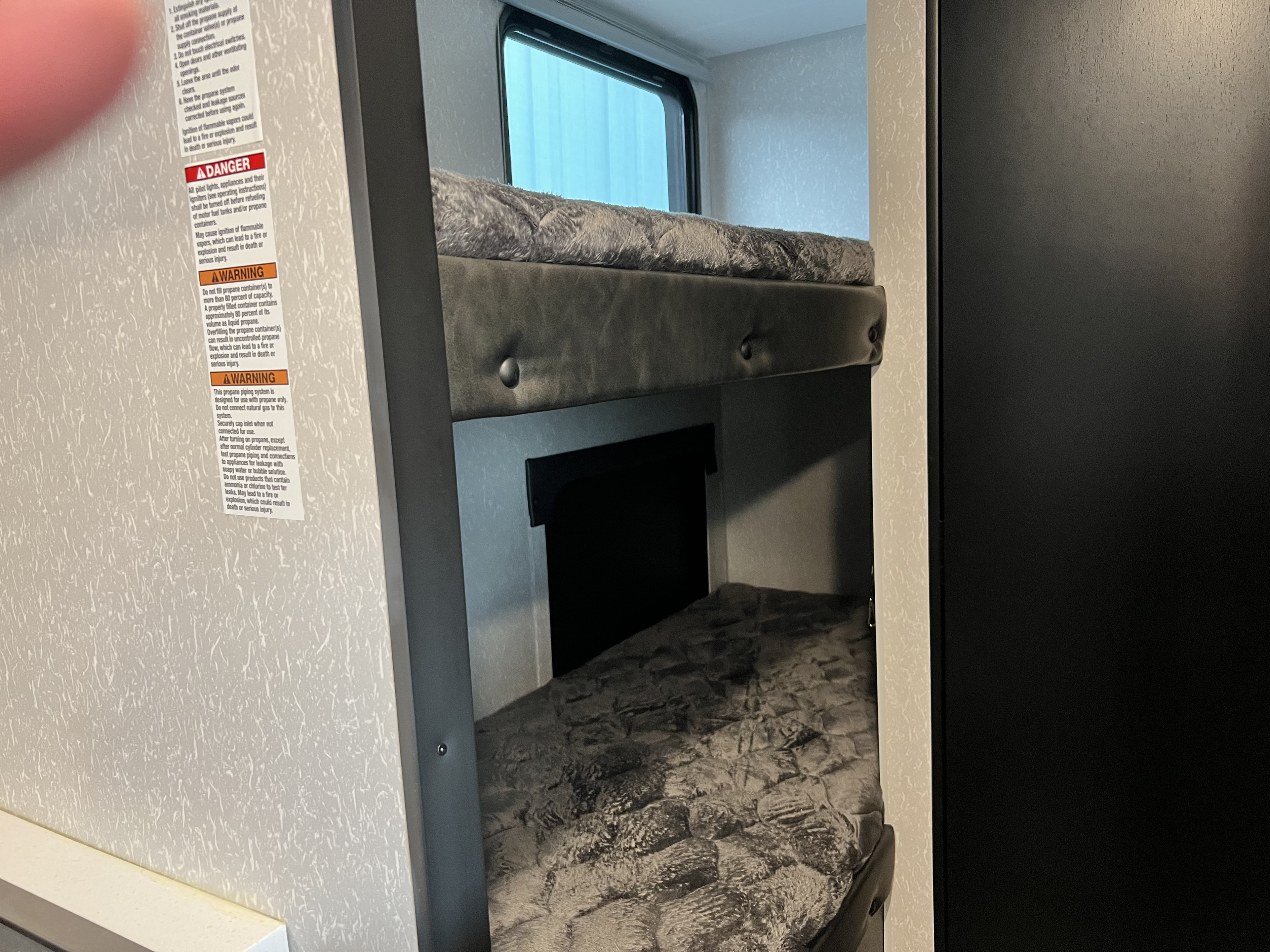 This RV rental interior features stacked bunk beds with soft gray mattresses, and clear propane safety warnings are visible on the wall.. Cherokee Wolf Pup #1 # 1 17jg 2023