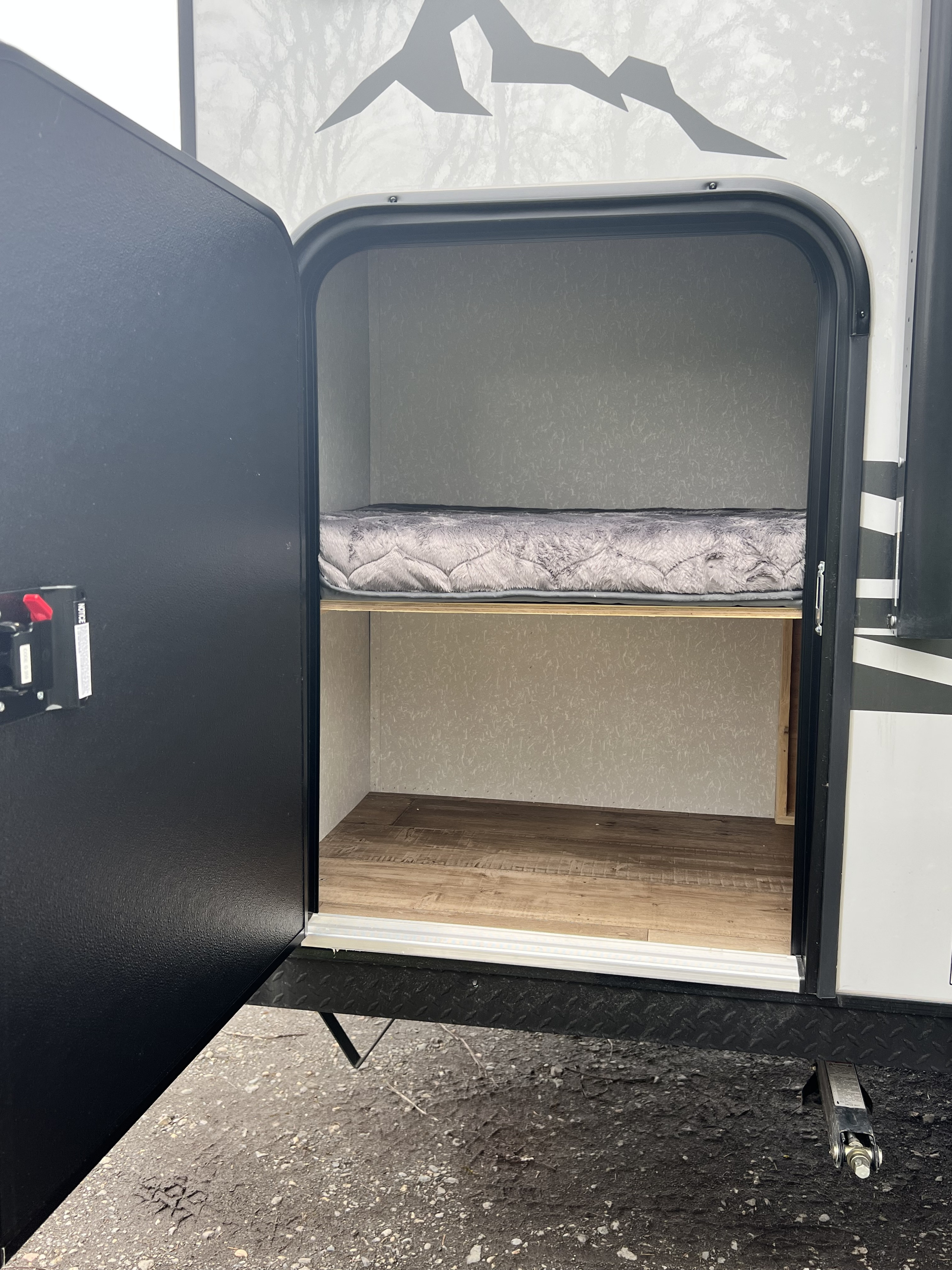 RV rental: Interior view of a versatile bunk/storage area, showing a soft mattress and wood-look flooring for gear.. Cherokee Pup Black label #3 17jgbl 2023