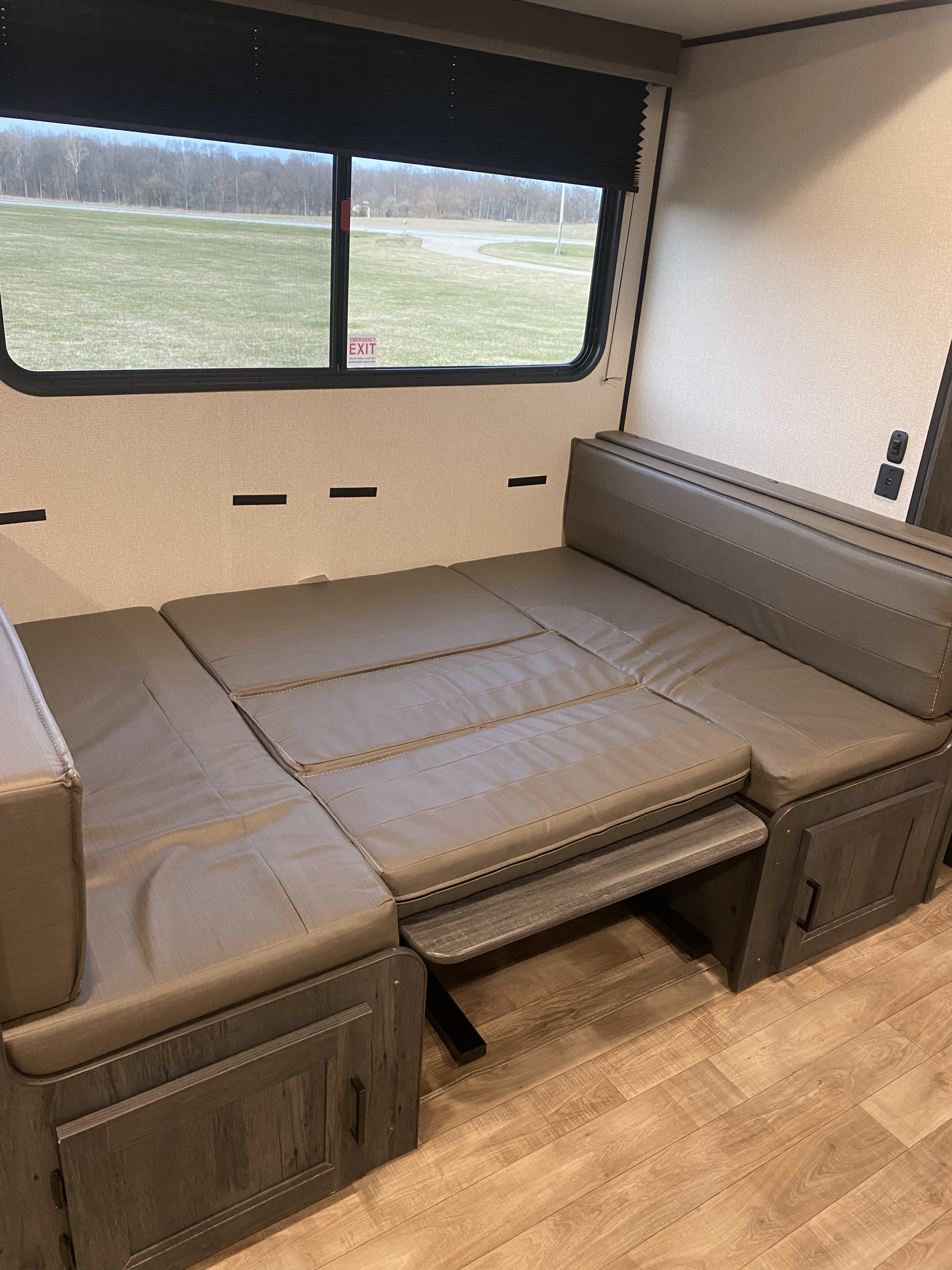 RV rental interior features a convertible dinette bed with storage, offering a comfortable sleeping area with a scenic window view.. Keystone hideout 29dfs 2023