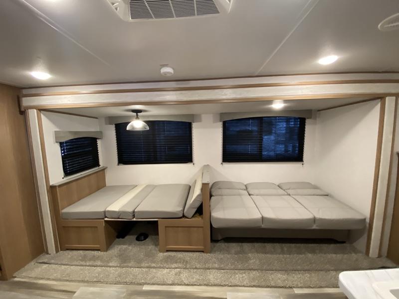 RV rental interior, showcasing two versatile convertible beds/dinettes with gray cushions & windows for comfortable travel.. Avenger LE 2022