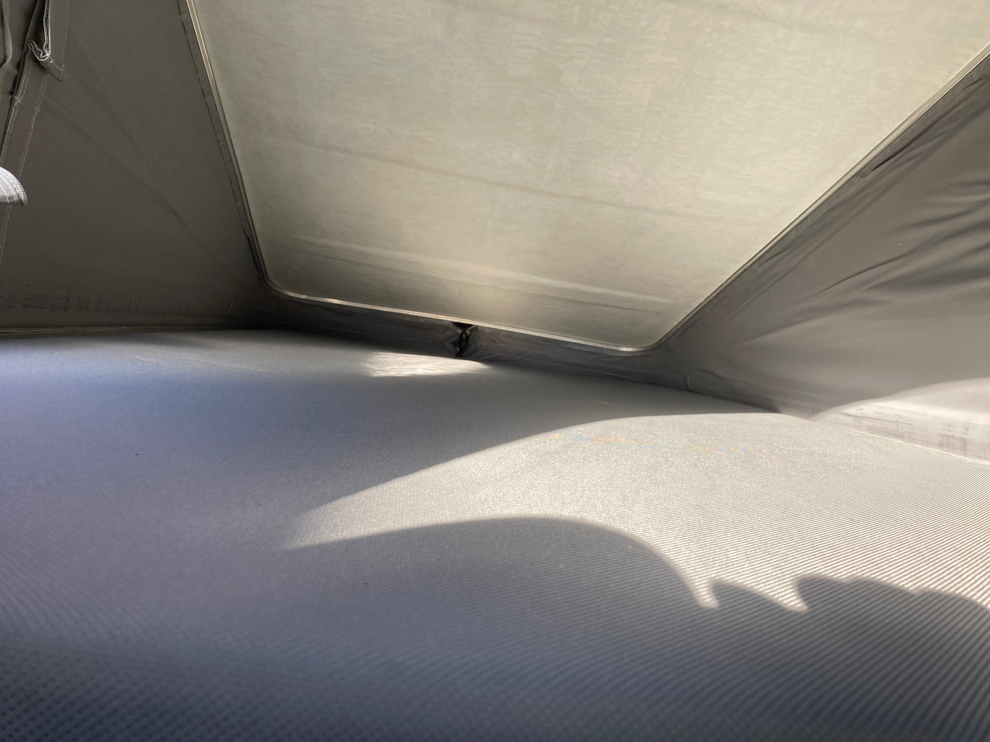 Experience an RV rental from within a cozy pop-top camper's sleeping space. Sunlight illuminates the textured gray floor.. Volkswagen Three bridges custom conversion 2016