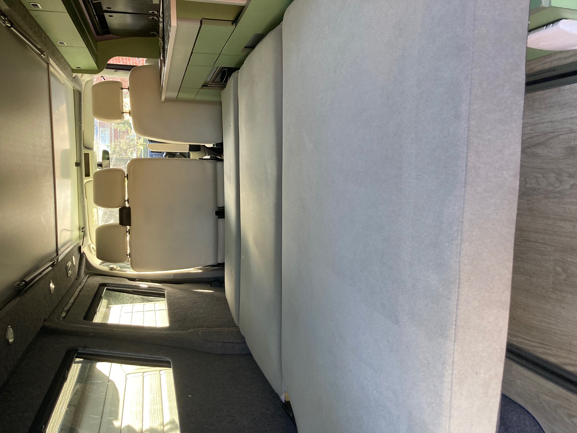 RV rental interior: Van's comfortable seating, convertible bed, overhead cabinets, and skylights for travel.. Volkswagen Three bridges custom conversion 2016