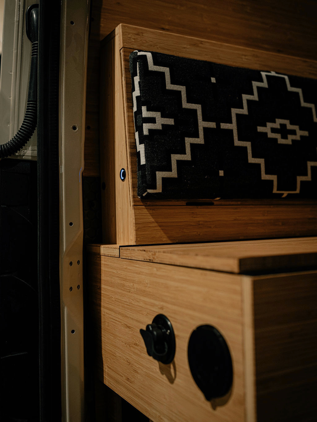 Sleek bamboo interior of an RV rental camper van, featuring a modern patterned cushion and integrated blue light.. Mercedes-Benz Sprinter 2022