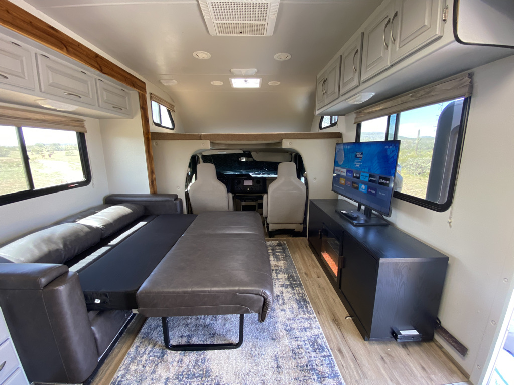 Spacious RV rental interior featuring a comfy sofa bed, TV, storage, and bright windows.. Four Winds Other 2011