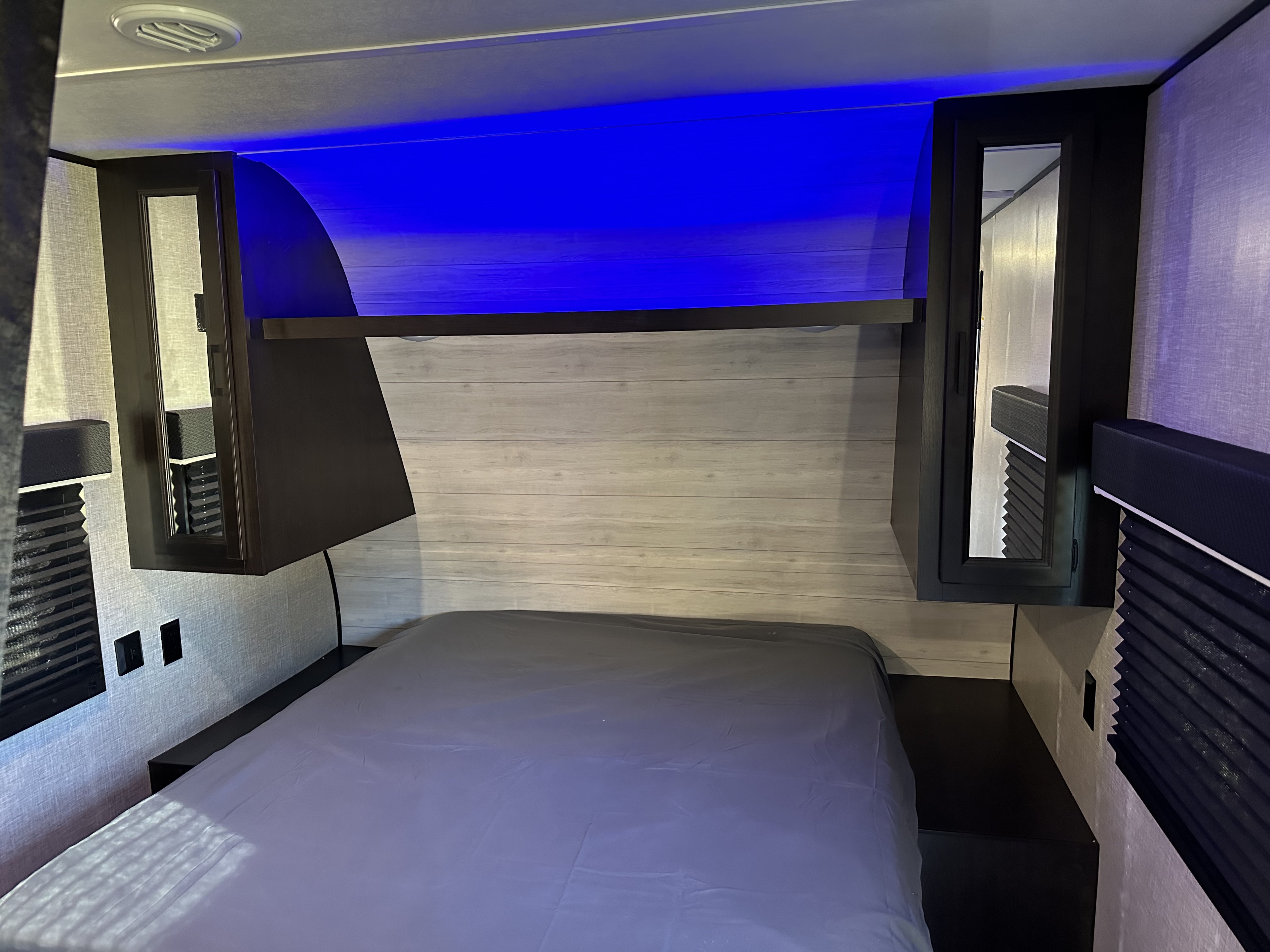 RV rental bedroom: a modern interior with a comfy bed, blue LED lighting, overhead storage, and convenient bedside outlets.. Jayco Jay Flight SLX 2022