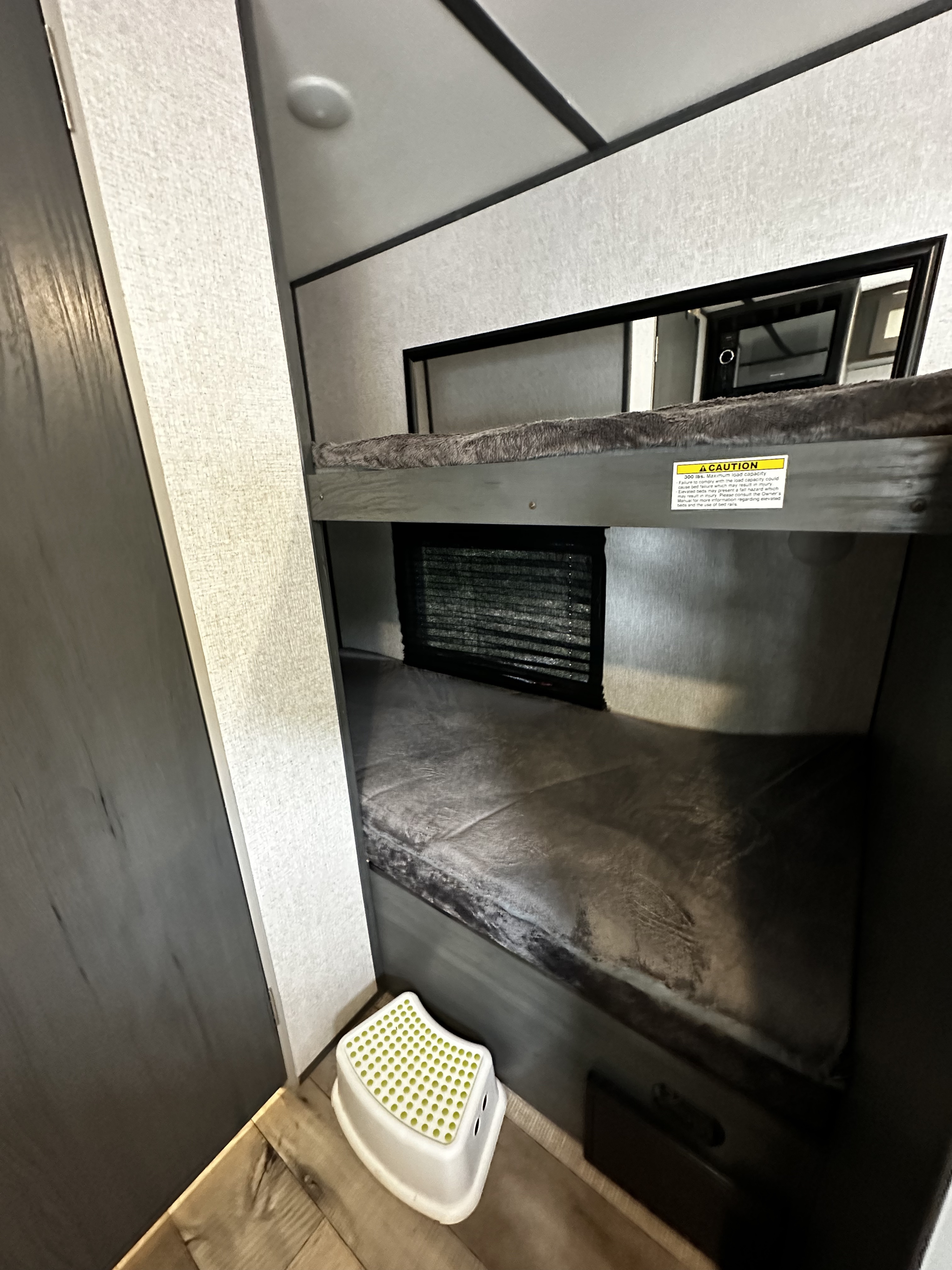 RV rental: Compact interior with cozy bunk beds, including safety warning & step stool for easy access.. Dutchmen Aspen 2021