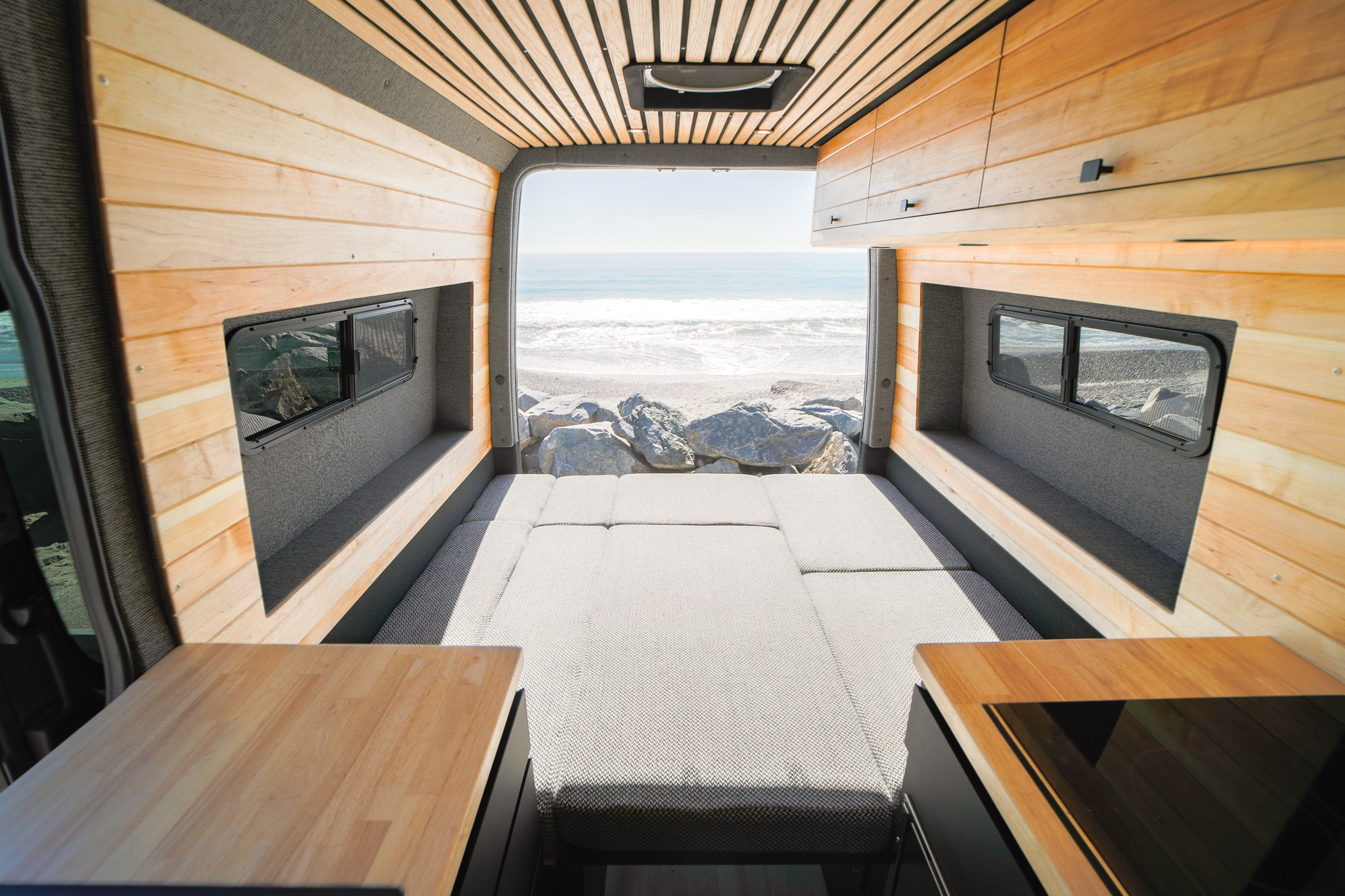 Stunning beach view from a cozy camper van RV rental with wood interior & comfy bed. Your adventure awaits!. Mercedes Sprinter 2021