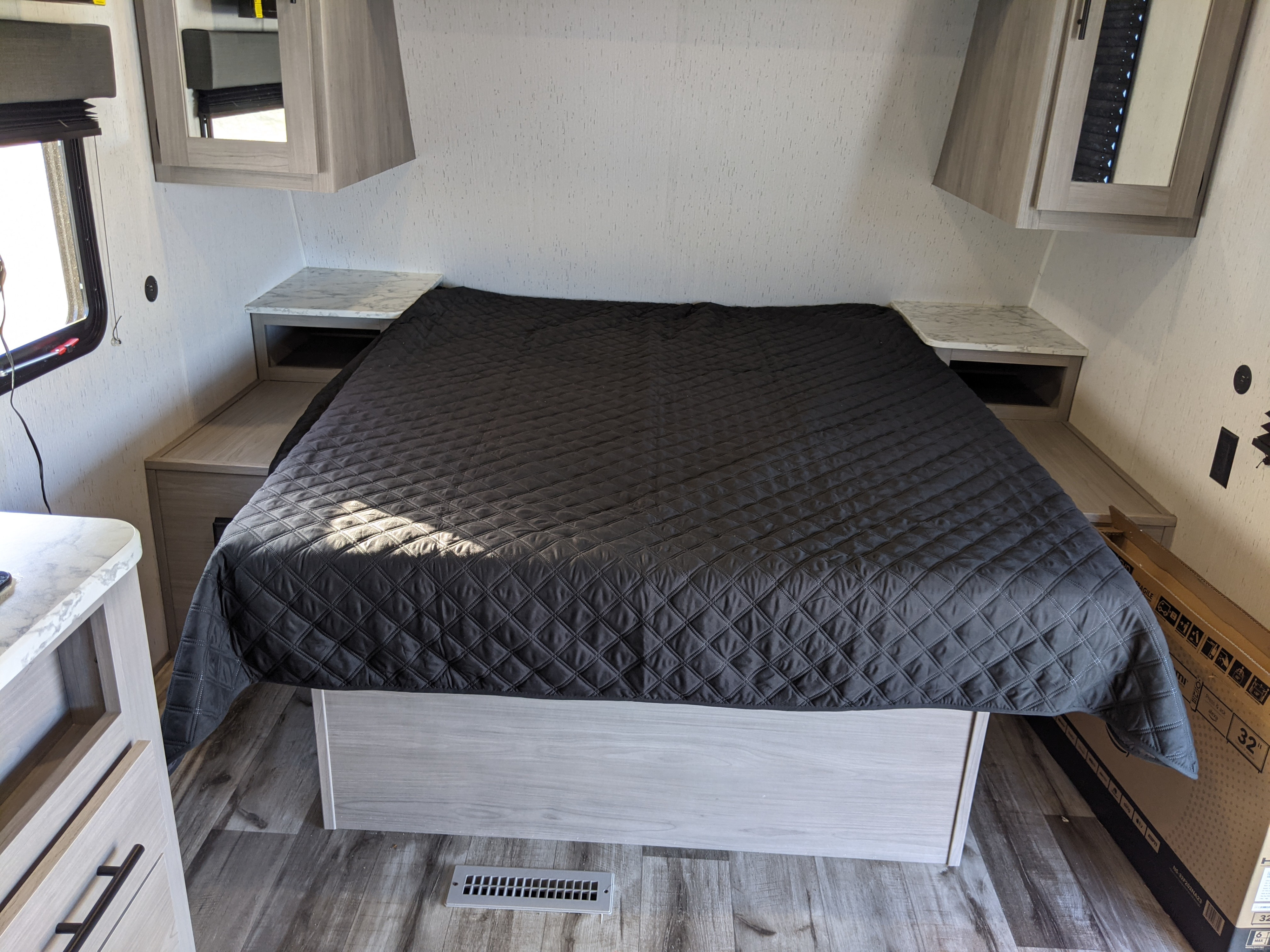 Comfortable RV rental bedroom featuring a large bed, nightstands, and overhead cabinets, ideal for travelers.. Keystone RV Coleman 214BH 2022