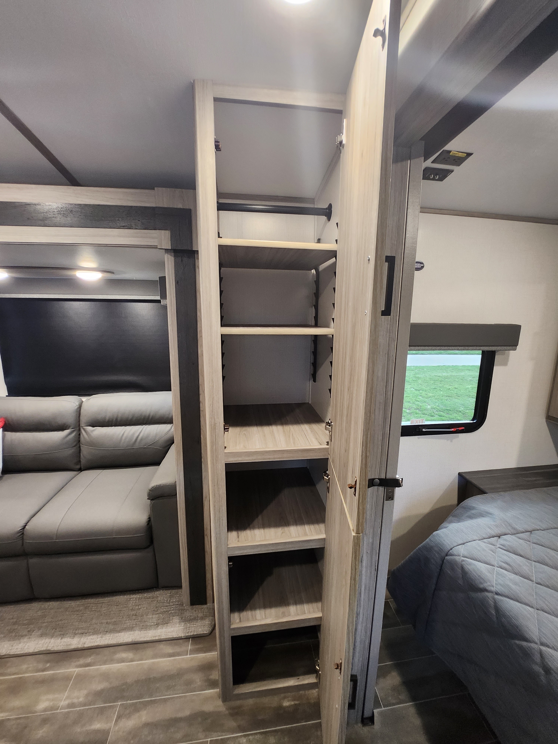 Explore this RV rental's versatile storage with an open closet, comfortable sofa, and a glimpse of the bedroom.. Keystone RV Passport GT Ultra Lite 2023