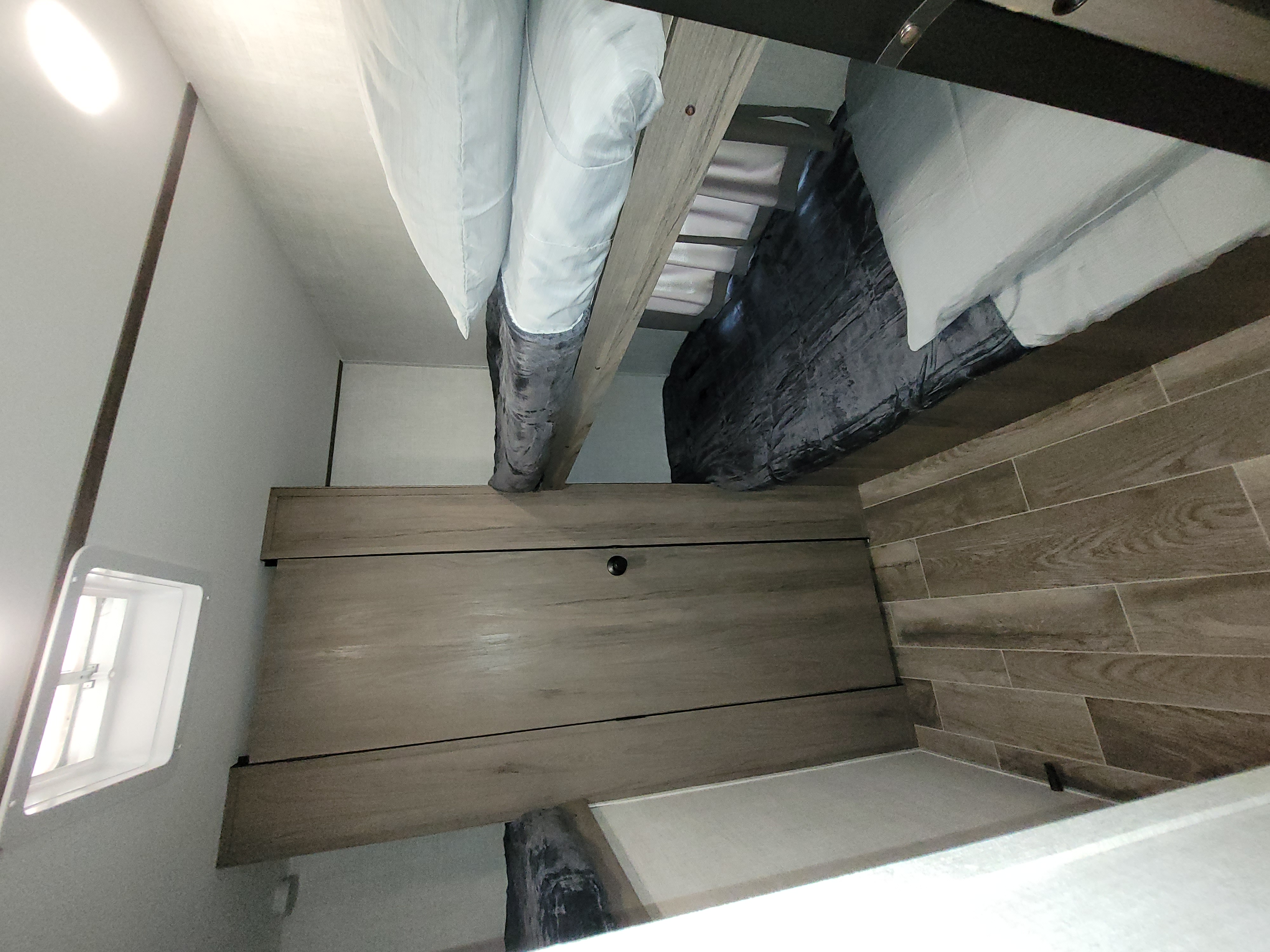 RV rental with cozy bunk beds, white pillows, dark blankets, wood-look floors, a cabinet, and window.. Gulf Stream Friendship 2022