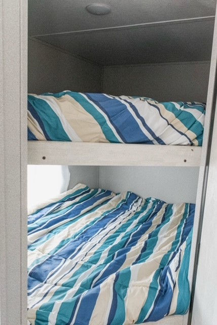 RV rental features: two bunk beds with blue/teal striped comforters, offering a cozy sleeping space for travel.. Grandriver 268BH 2023