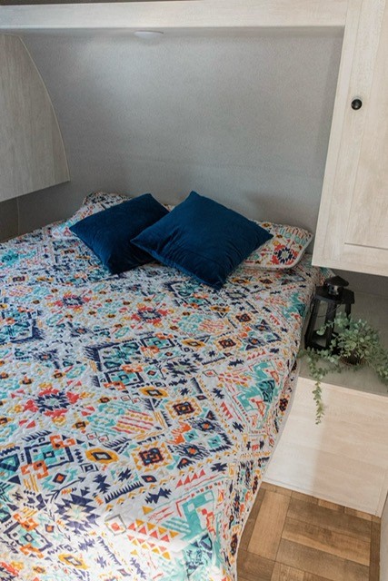 Cozy RV rental bedroom with colorful bedding, blue pillows, and decorative lantern for a comfortable stay.. Grandriver 268BH 2023