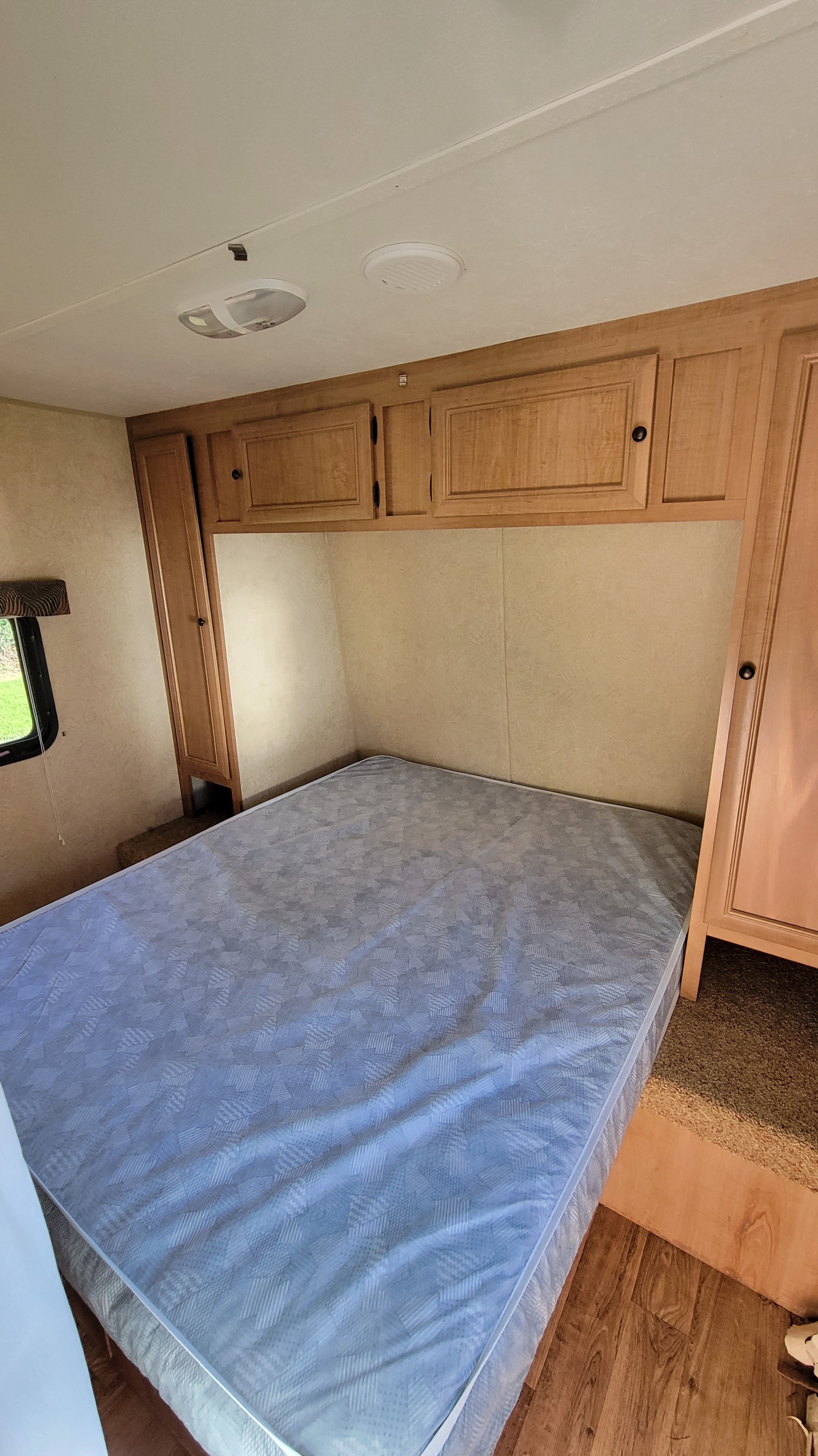 Clean RV rental bedroom featuring a full-size bed, ample storage, and a window for natural light.. Skycat Skycat Trailer 2014