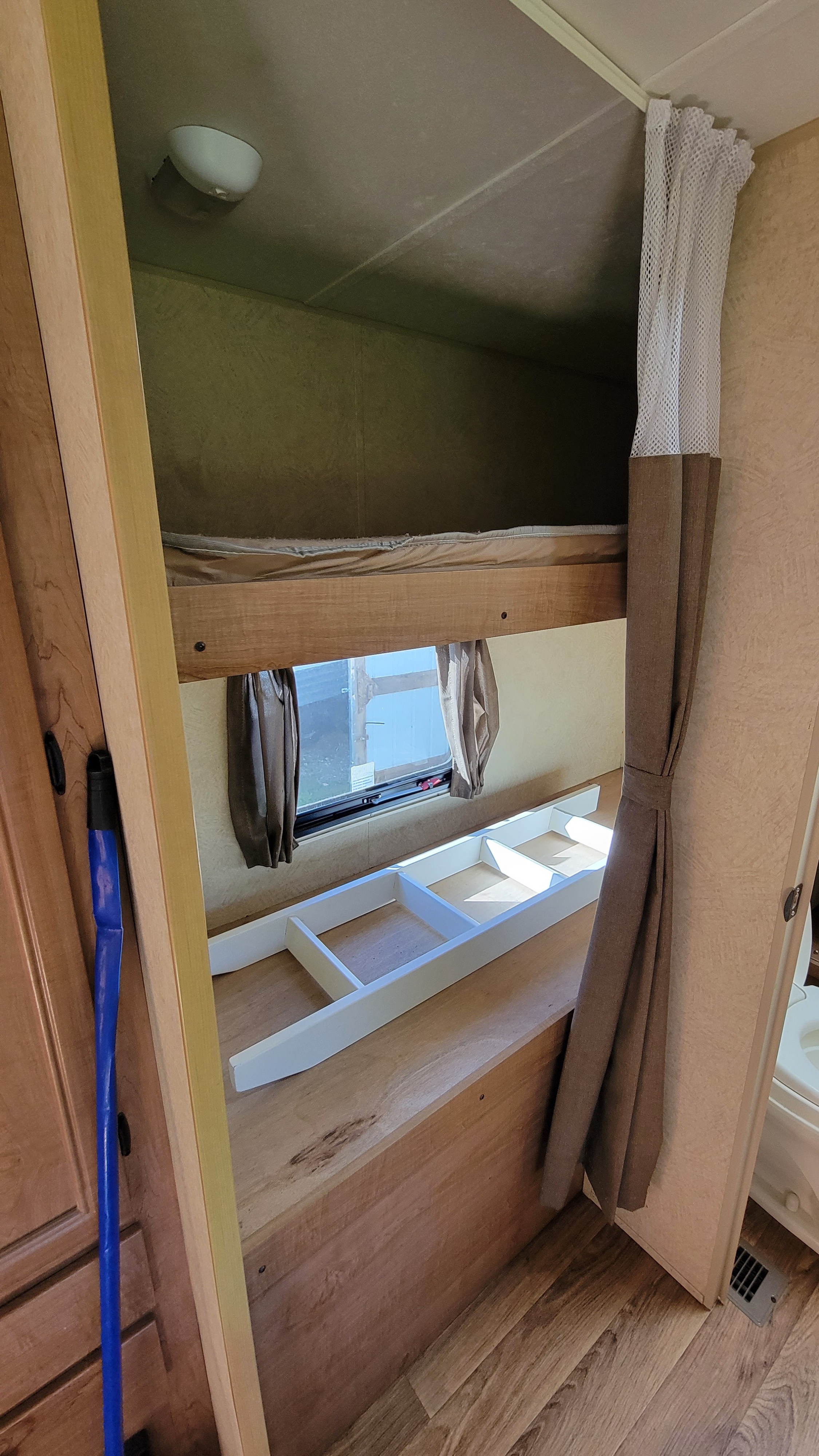 Inside an RV rental: lower bunk with a ladder, upper bunk bed, window with curtains, and wood-look flooring.. Skycat Skycat Trailer 2014