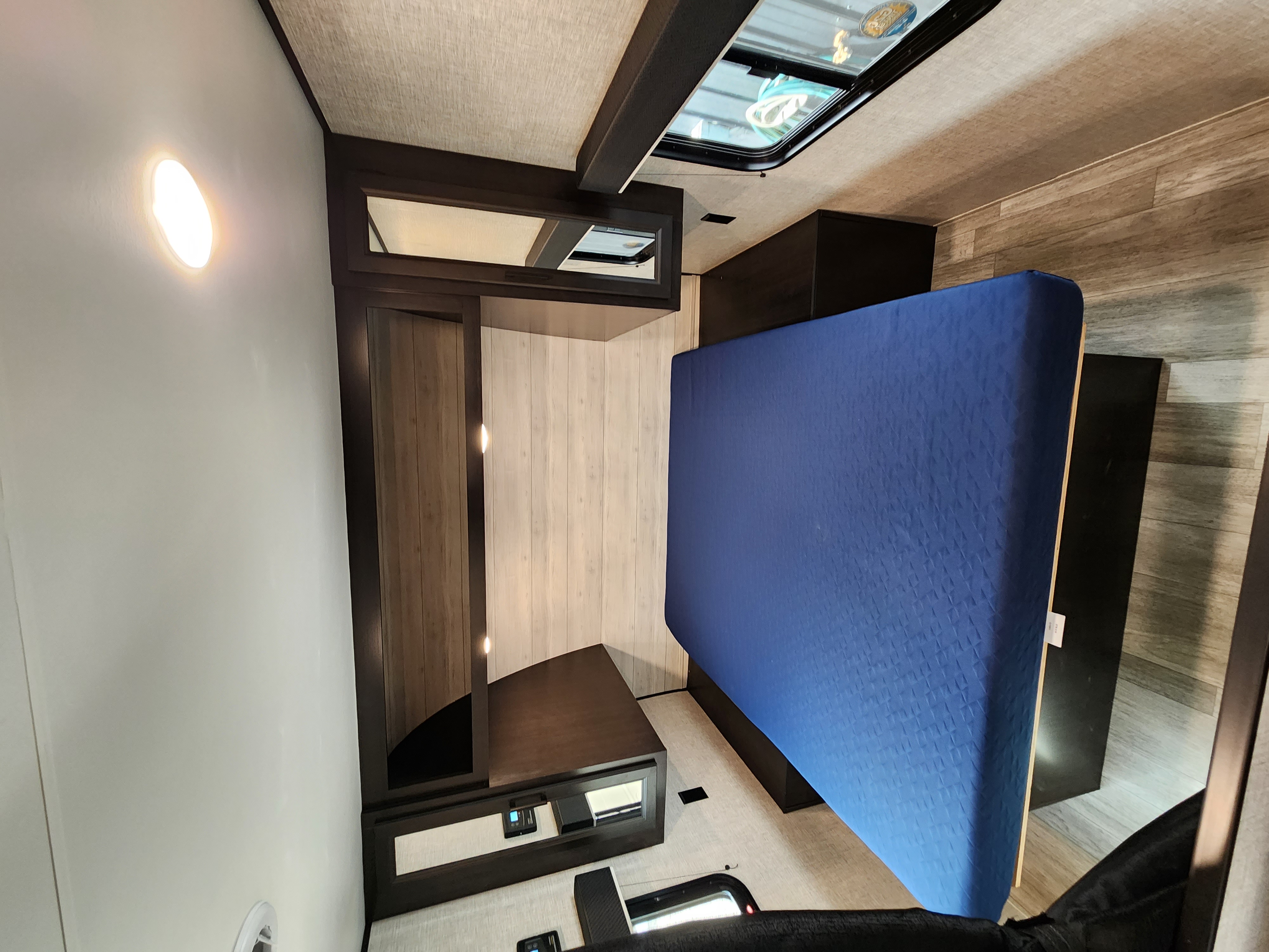 Inside an RV rental: a modern bedroom featuring a comfortable blue mattress, ample storage, and natural light from a skylight.. Jayco Jay Flight 2023