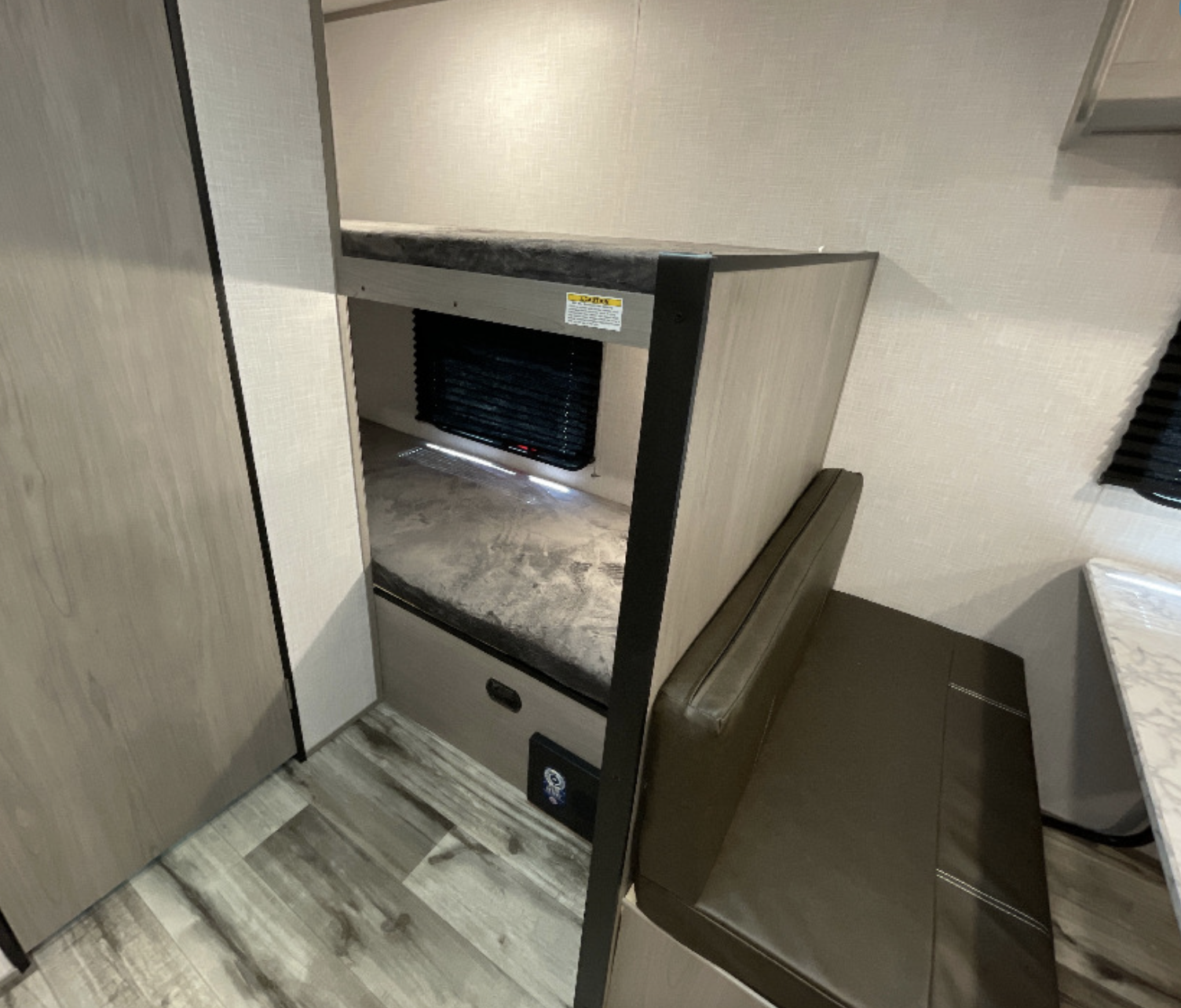 Compact RV rental interior featuring cozy bunk beds and a functional dinette area.. Dutchmen Coleman Lantern LT 2023