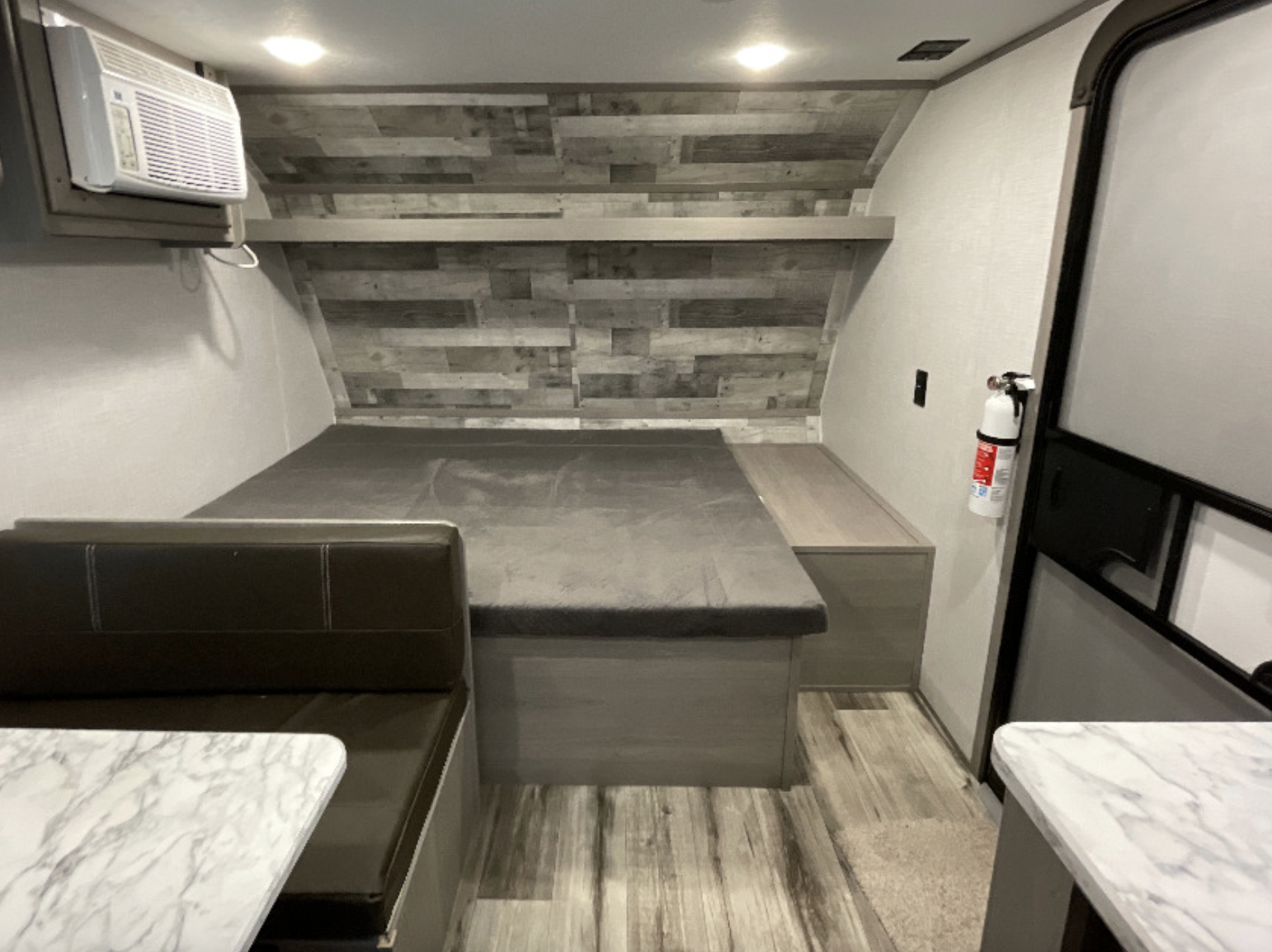 This RV rental interior features a bed, dinette, AC unit, and fire extinguisher, offering a comfortable space.. Dutchmen Coleman Lantern LT 2023