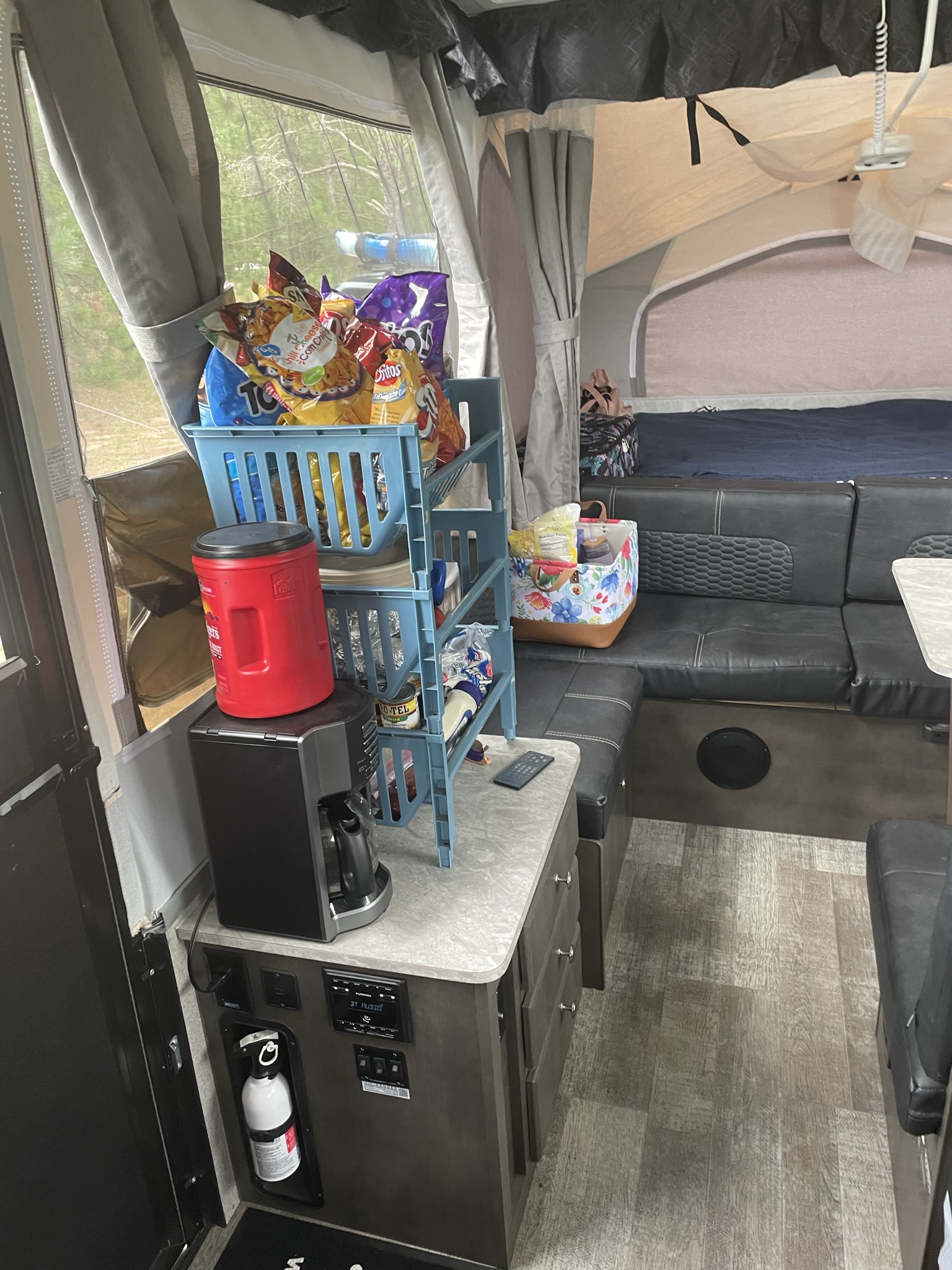 RV rental interior showing a pop-up bed, lounge area, and kitchen counter with snacks and a coffee maker. Great for travel.. Forest River Rockwood ESP 2020