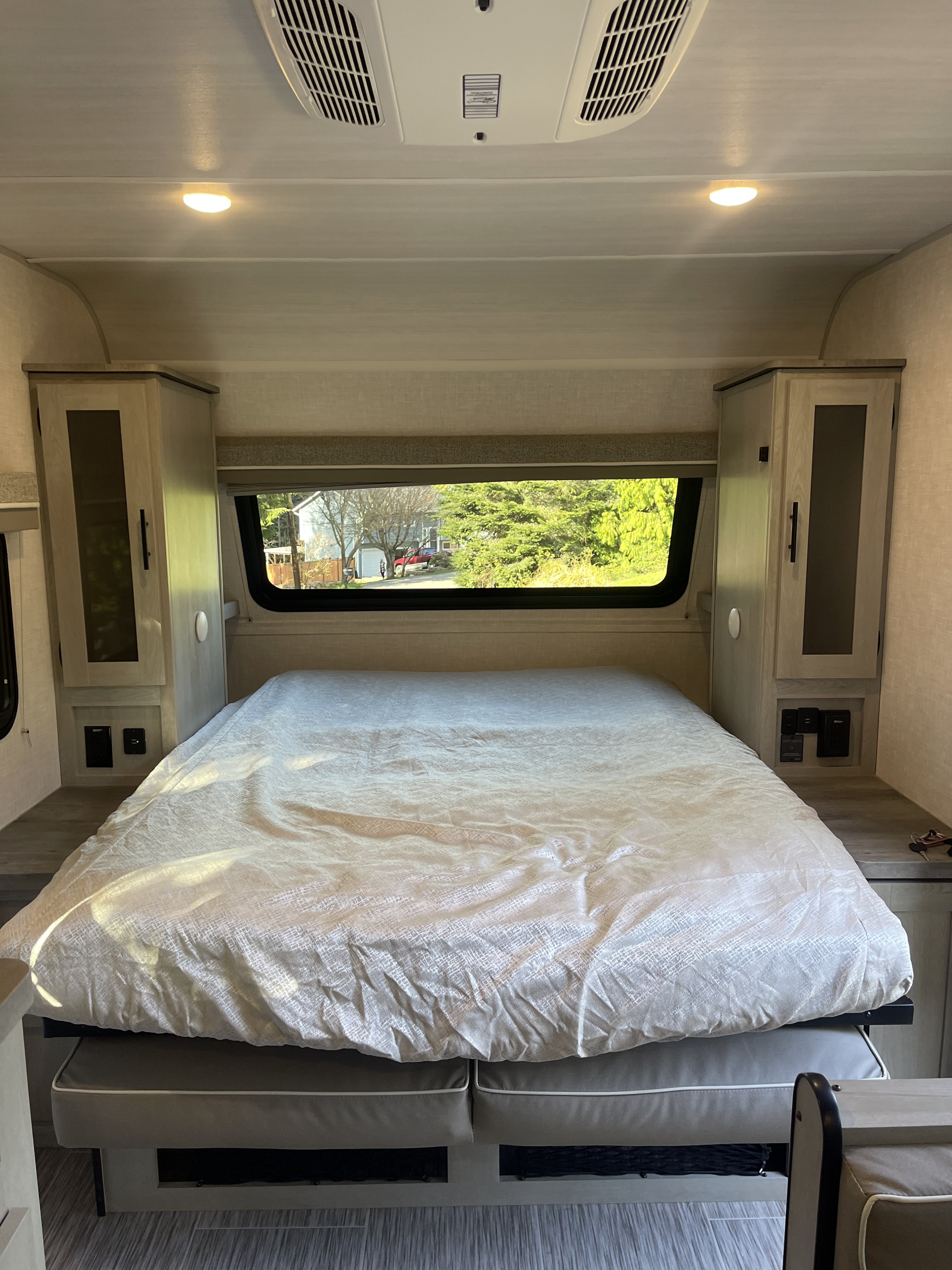 RV rental: A bright, comfortable bedroom with a large bed, window view, and convenient integrated storage.. Forest River Ibex 2021