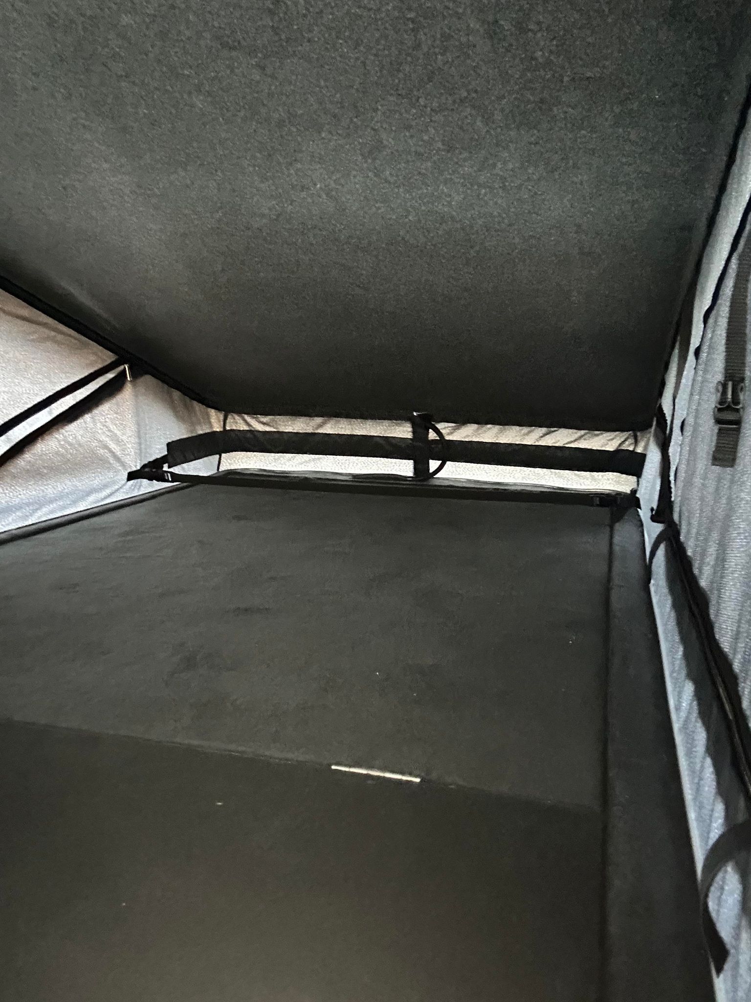 Inside an RV rental pop-up tent: a dark mattress, fabric walls, and ceiling define this camping sleeping area.. Volkswagen Other 2023