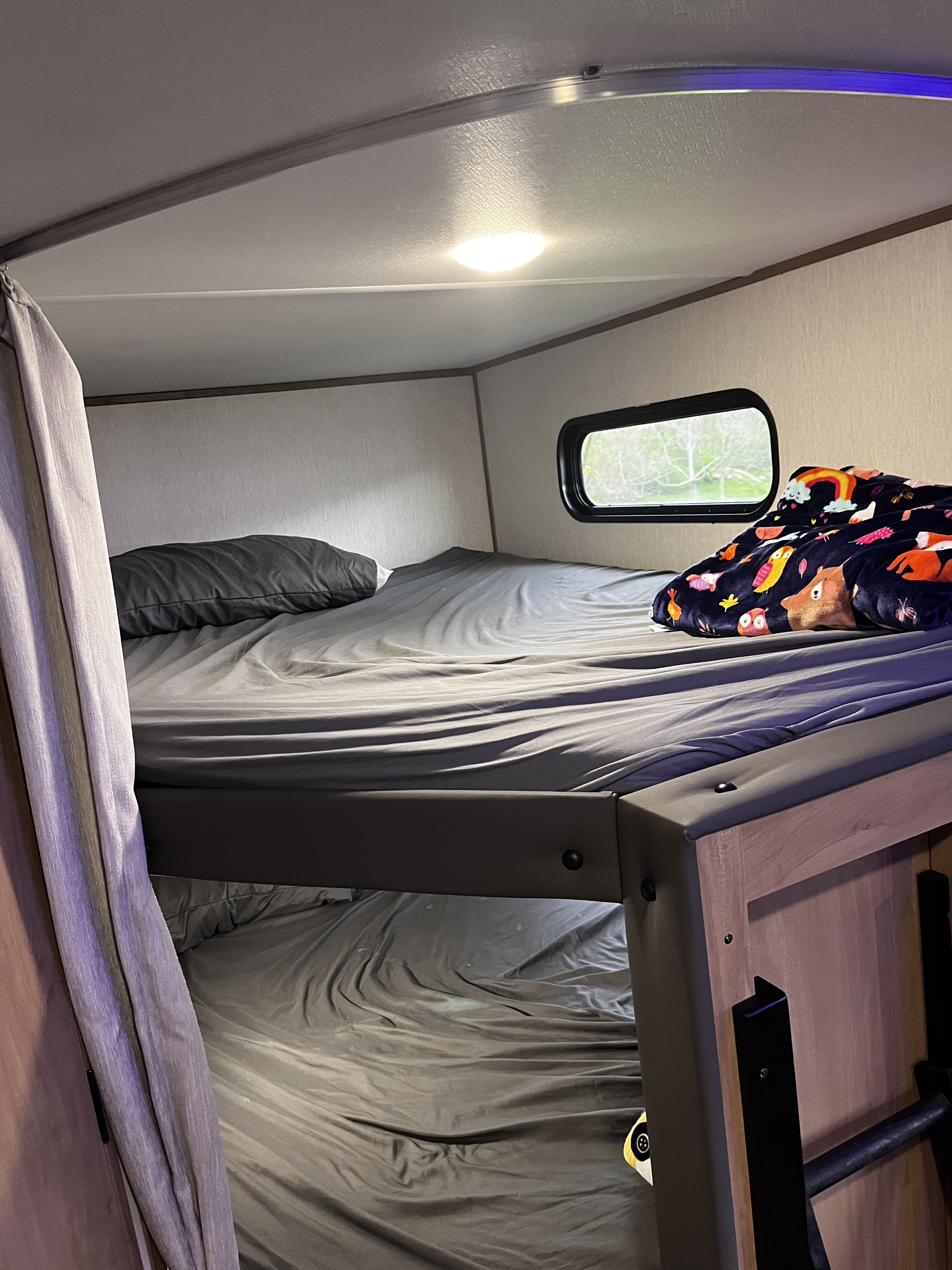 Cozy RV rental bunk beds with soft bedding & window view. Perfect for family adventures in a travel trailer interior.. Forest River Cherokee 26 dbh-l 2023