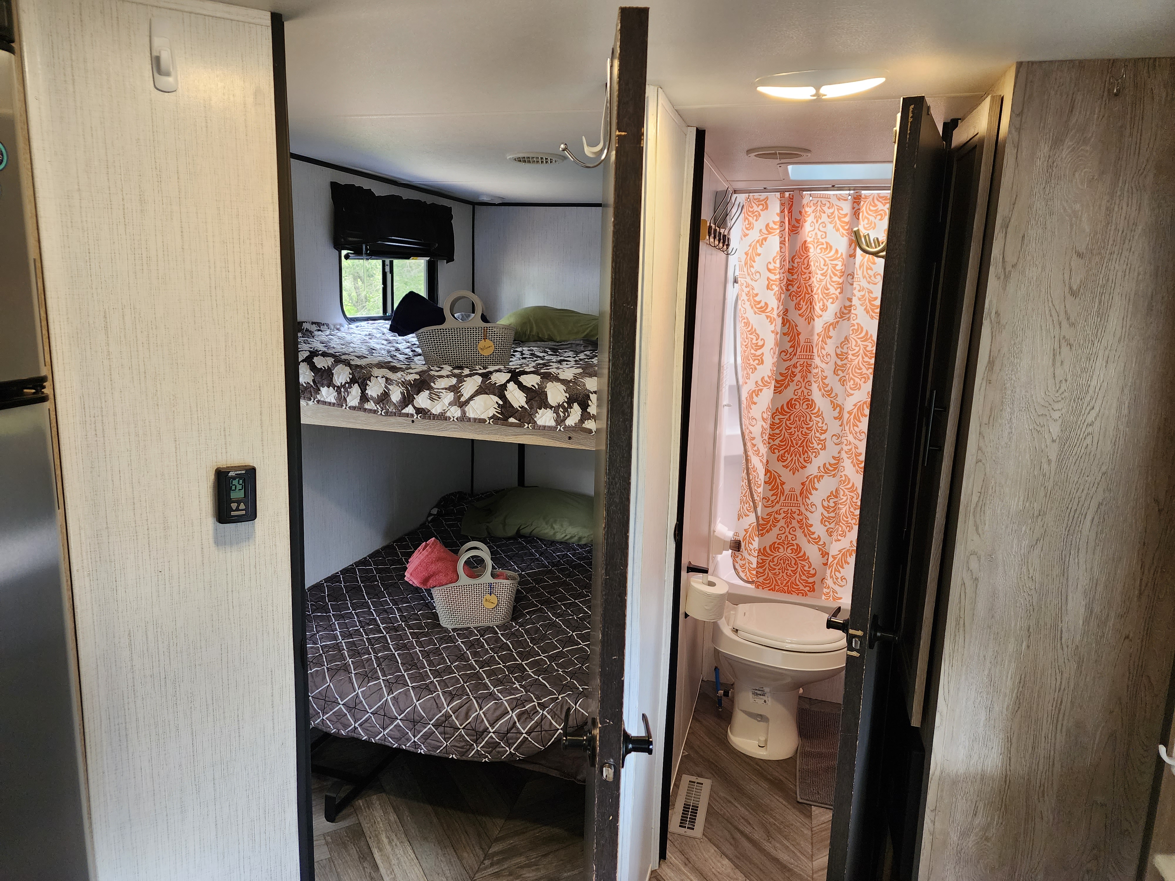Cozy RV rental interior featuring bunk beds with bedding and a compact bathroom with shower & toilet.. Heartland RVs Prowler 2022