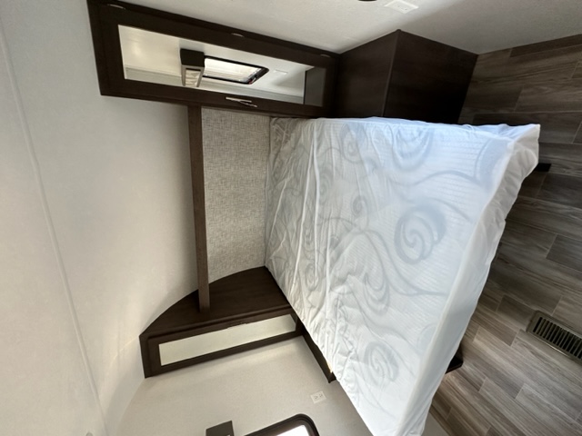 RV rental bedroom: A comfortable white bed with patterned mattress, overhead storage, and wood-look flooring.. Salem 26DBLE 2019