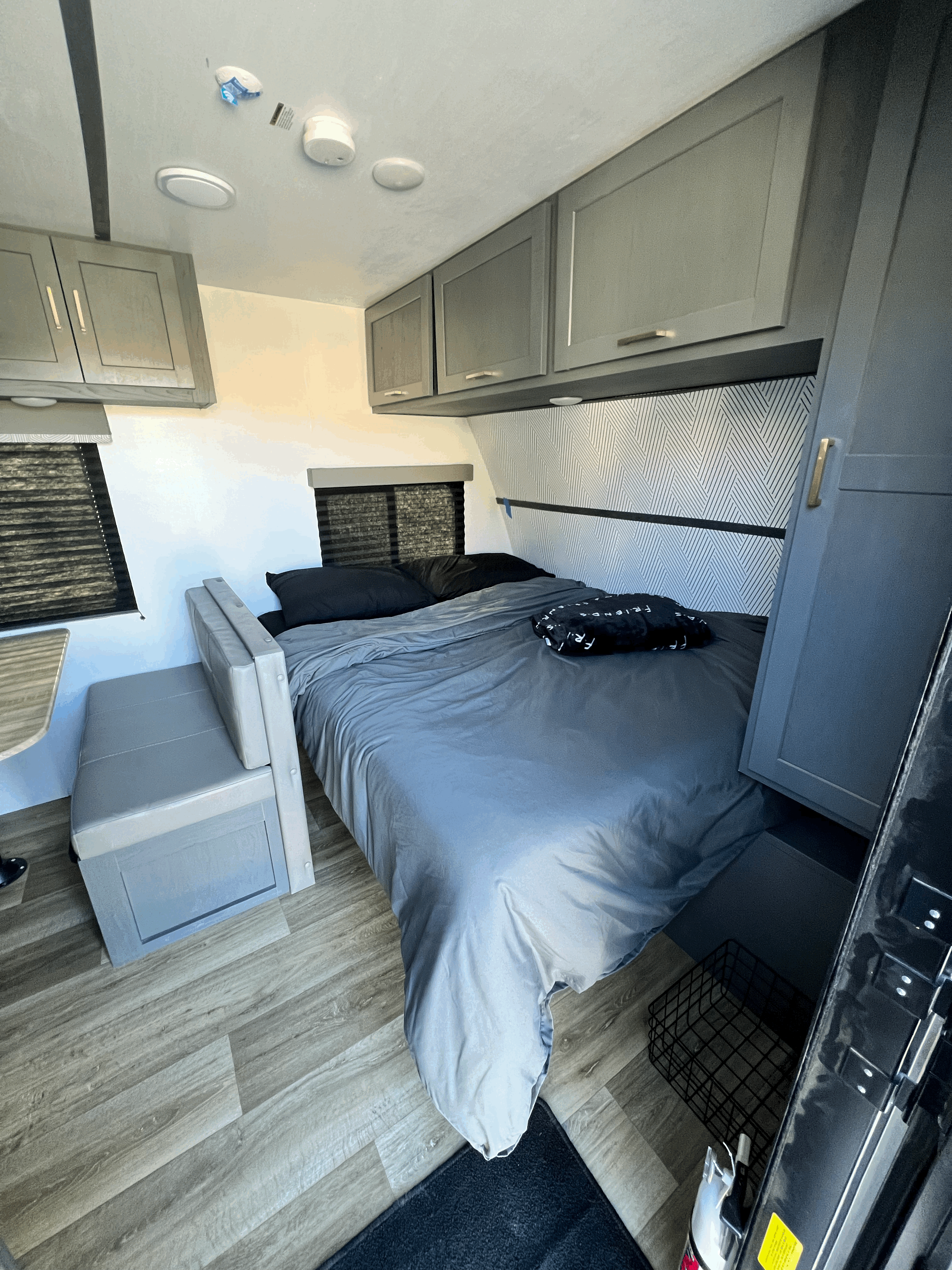 Explore this modern **rv rental**'s interior: a comfortable grey bed, overhead cabinets, and a versatile dinette seating area. Ideal for travel.. Keystone RV Bullet Crossfire 2022