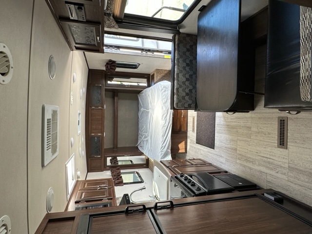 Spacious RV rental interior: kitchen with stove, dining area, and bedroom with bed. Perfect for travel.. Palomino Solaire 211BH 2018