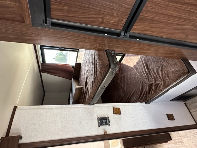 RV rental interior with brown bunk beds, a compact sleeping area, and a window.. Palomino Solaire 211BH 2018