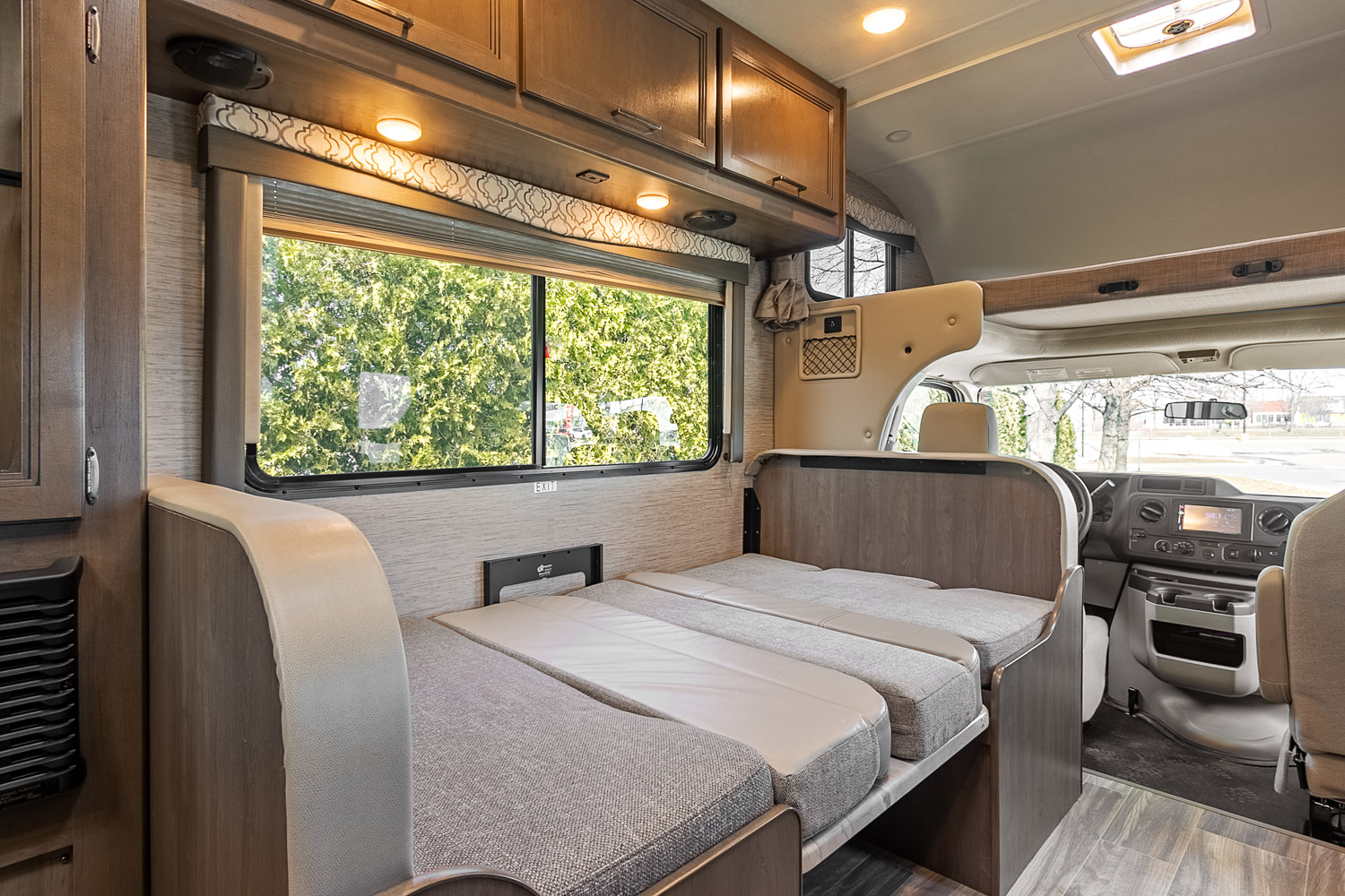 Spacious RV rental interior with a versatile bed/seating area, large window, and overhead storage. Ideal for travel.. Thor Freedom Elite 2021