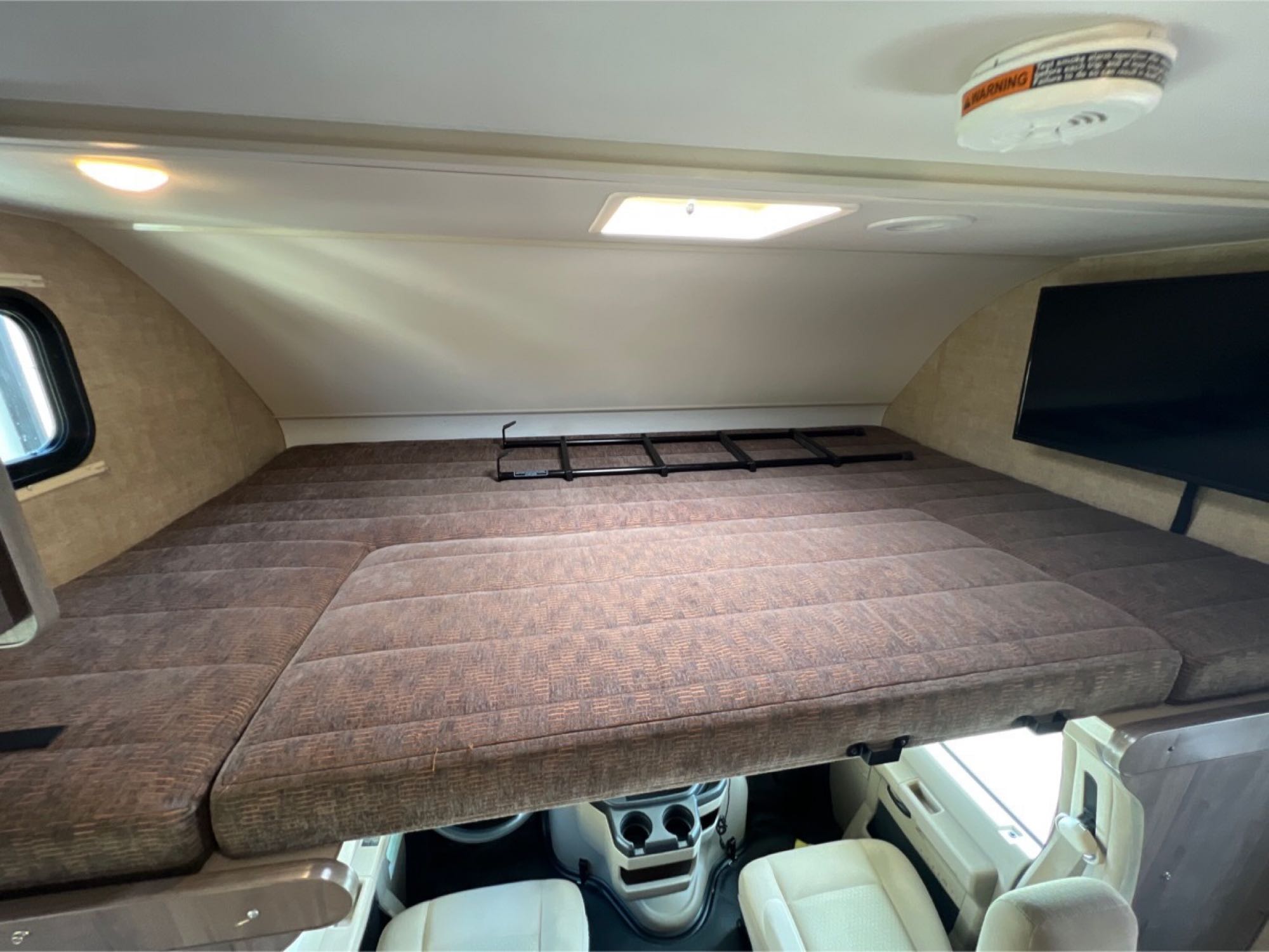 Inside this RV rental, a large, comfortable cab-over bunk bed with a TV, window, and skylight offers a cozy sleeping space.. Winnebago Minnie Winnie 2019