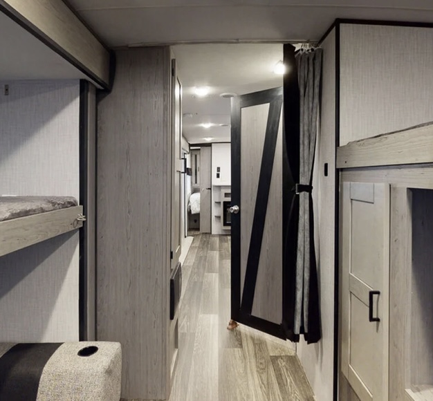 Bunk above on right side with storage and tv center underneath. Left side has fold down bed and arm chairs on the floor that unfold into a queen bed. . Heartland RVs Mallard 2021