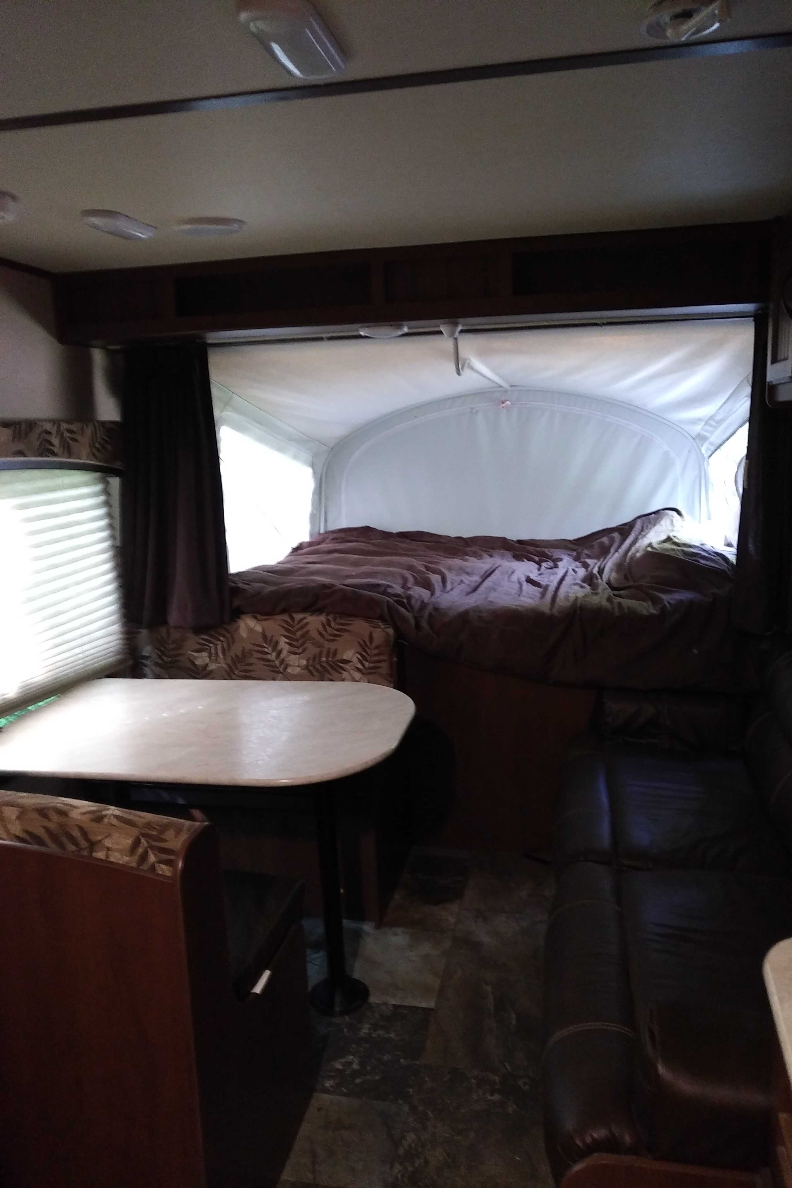 Inside an RV rental, featuring a cozy dinette, expanded pop-out bed area, and comfortable sofa seating.. Other Other 2015
