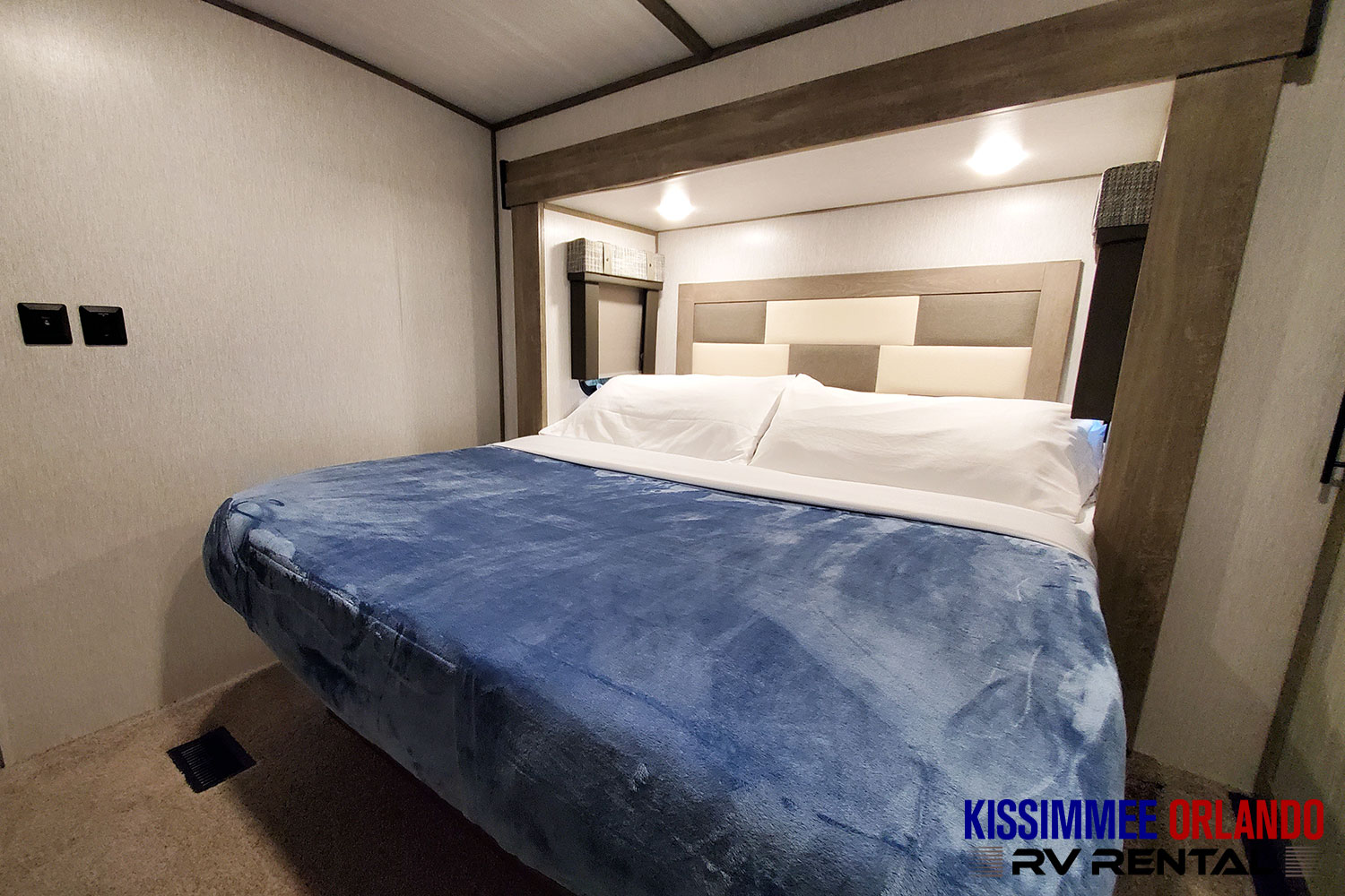 Cozy RV rental bedroom with a large, comfortable bed, white sheets, blue blanket, overhead lighting, and storage nooks.. Forest River Salem Hemisphere 2022