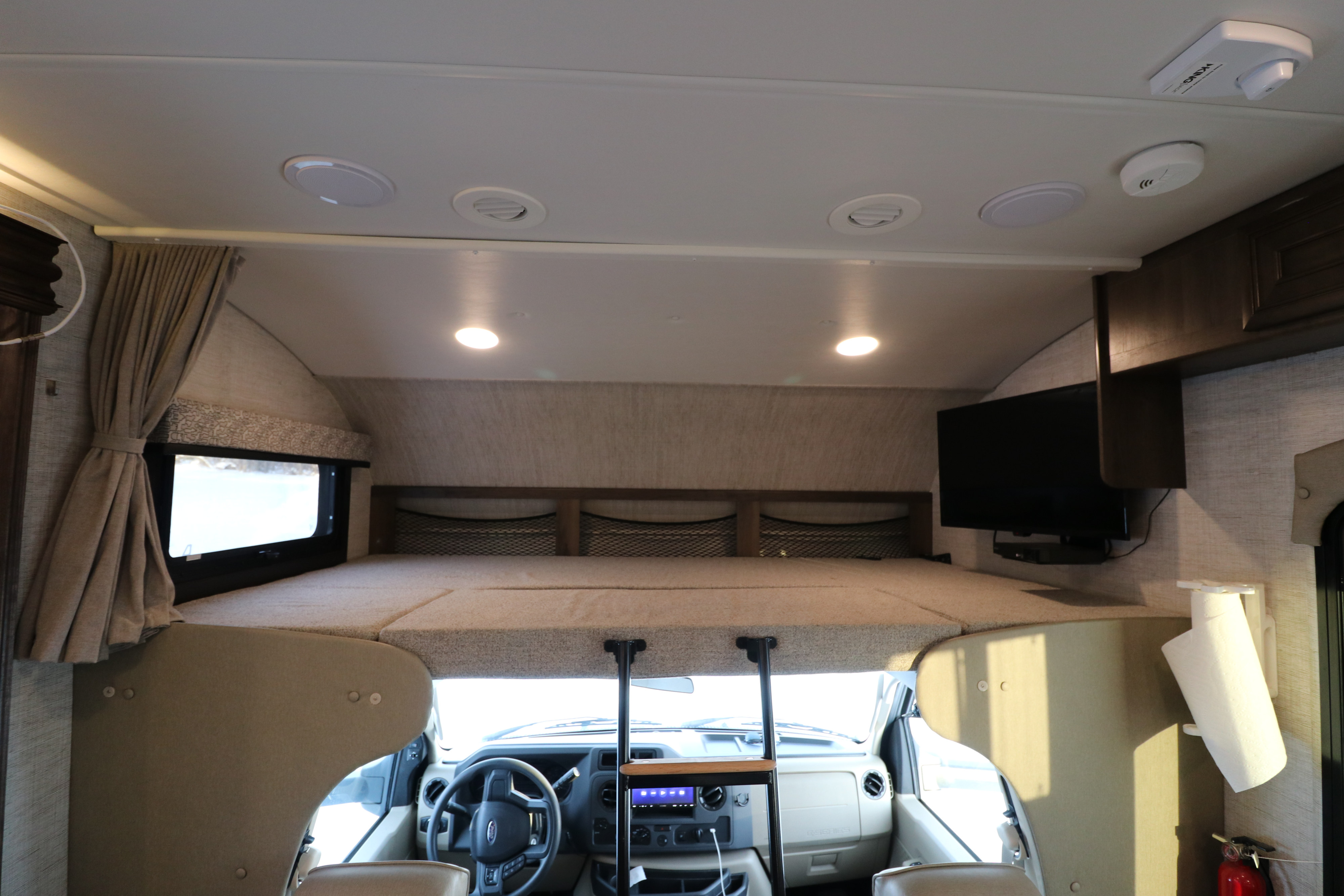 Comfortable rv rental interior featuring a large overhead bunk, driver's cockpit, flat-screen TV, and ample storage.. Jayco Greyhawk 2021