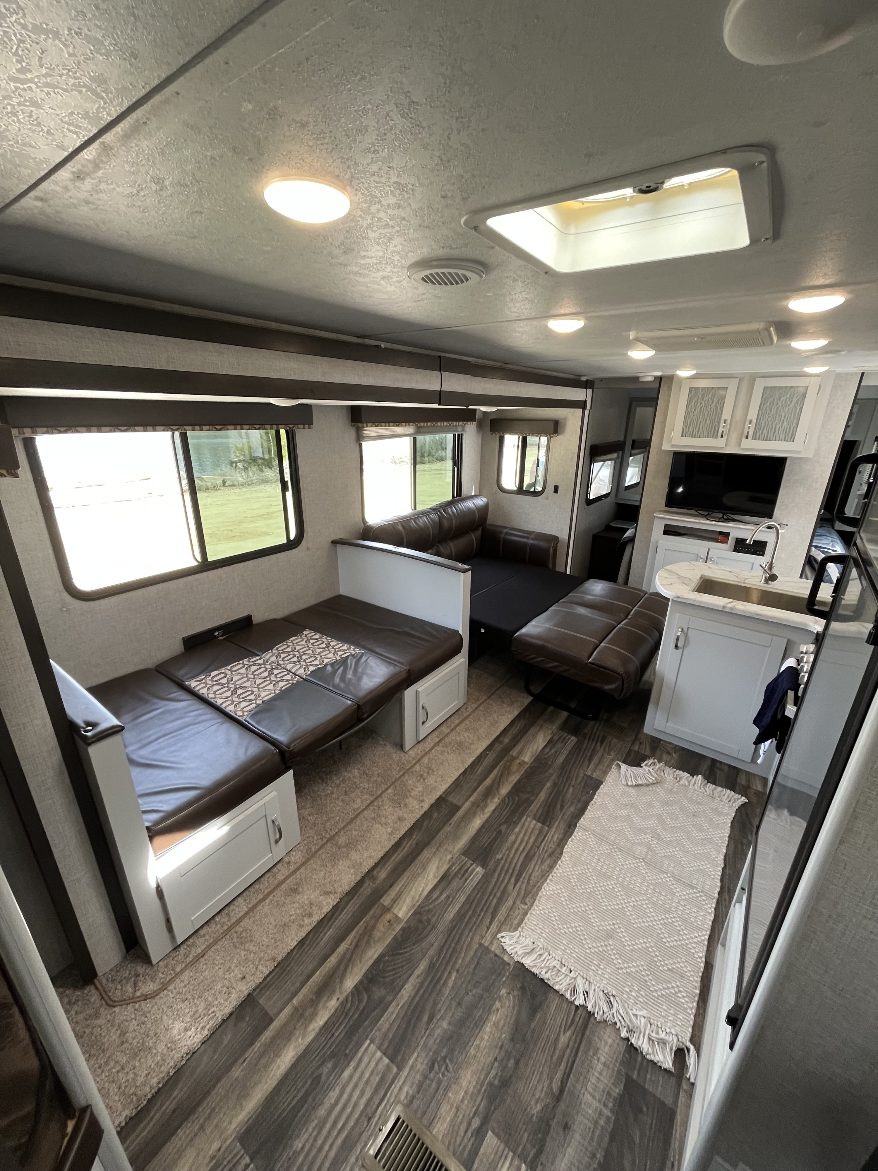Spacious RV rental interior featuring convertible dinette, sofa, kitchenette, and bright windows.. Keystone RV Bullet Ultra Lite 2019