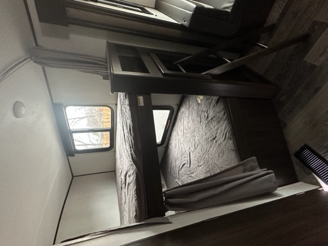 Inside an RV rental: view of sturdy bunk beds, a window, and a compact living area for travelers.. Keystone RV Springdale 2021