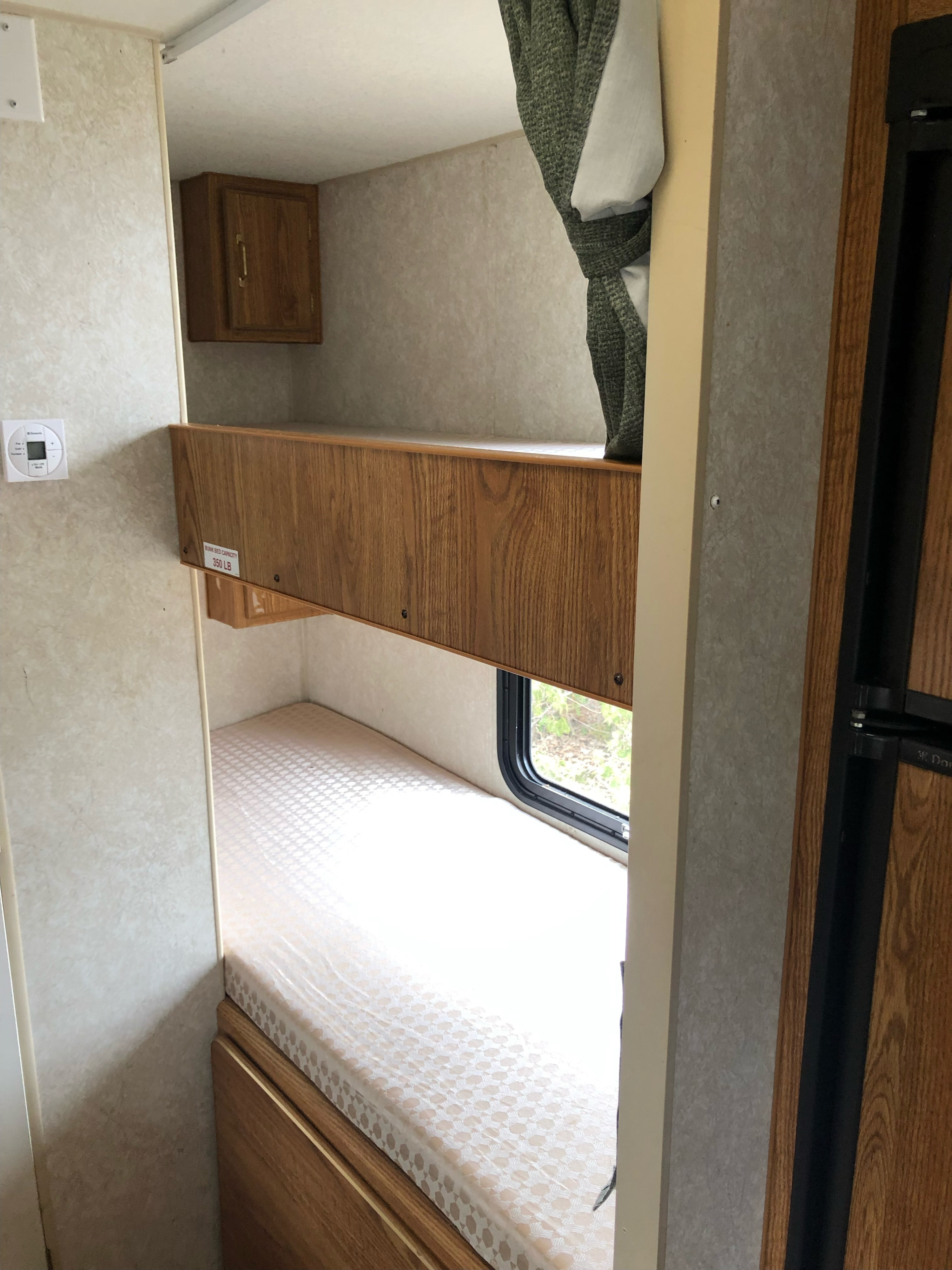 RV rental interior: sturdy bunk beds, 350 lb capacity, with a lower window, creating a compact sleeping space.. Wilderness Lite 2003