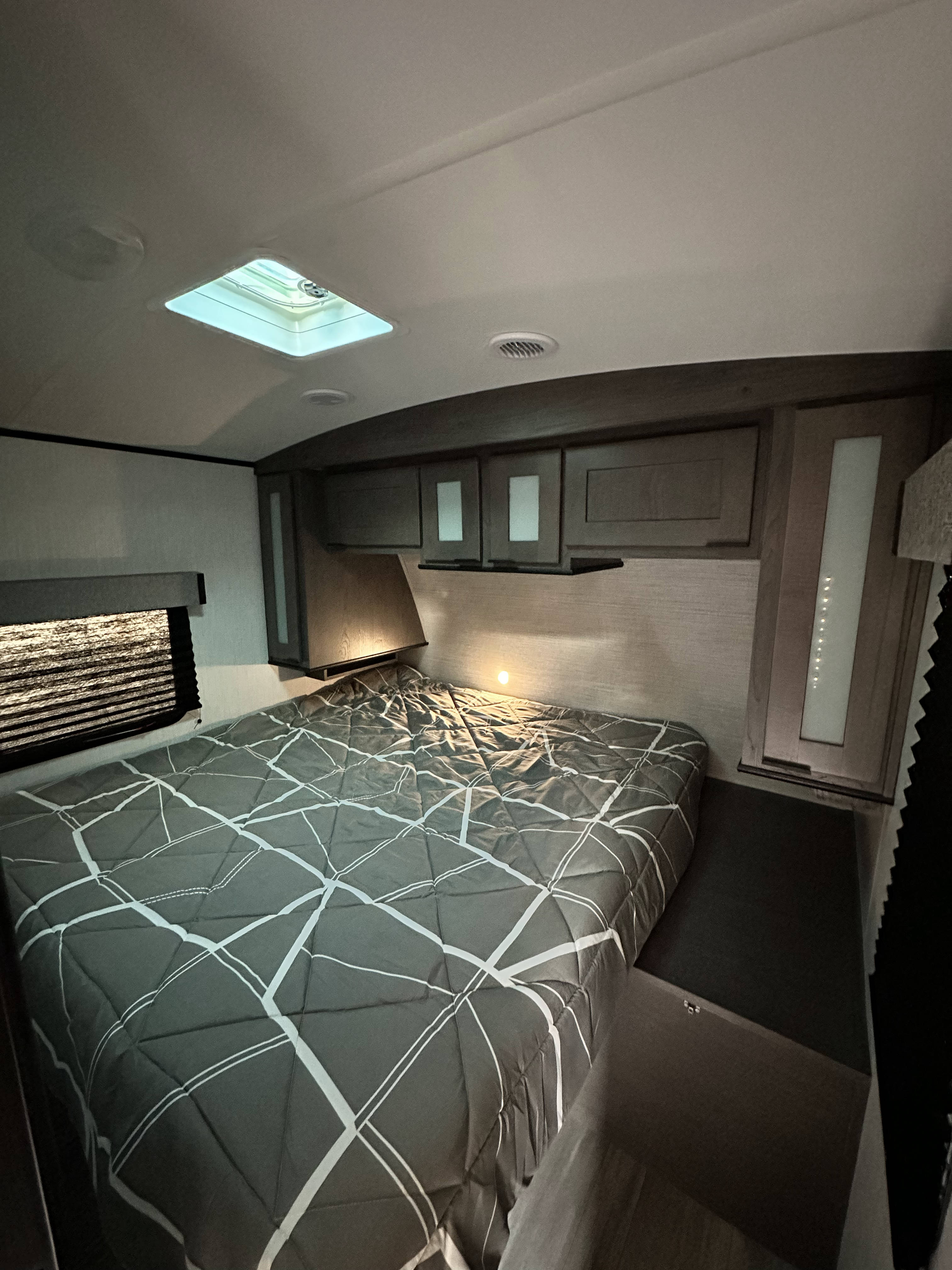 Inside an RV rental, this cozy bedroom features a bed with grey patterned comforter, overhead storage, and a skylight.. Cruiser RV MPG Ultra Lite 2022