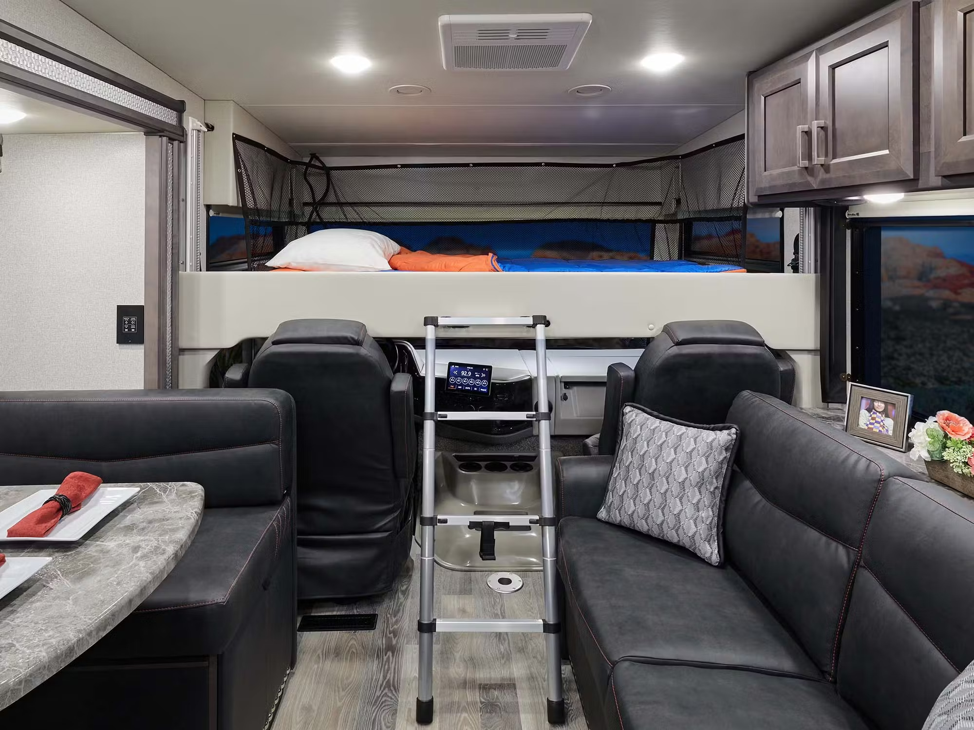 Comfortable RV rental interior with a bed above the cockpit, dining area, and living space. Perfect for your road trip.. Thor Motor Coach Outlaw 2022