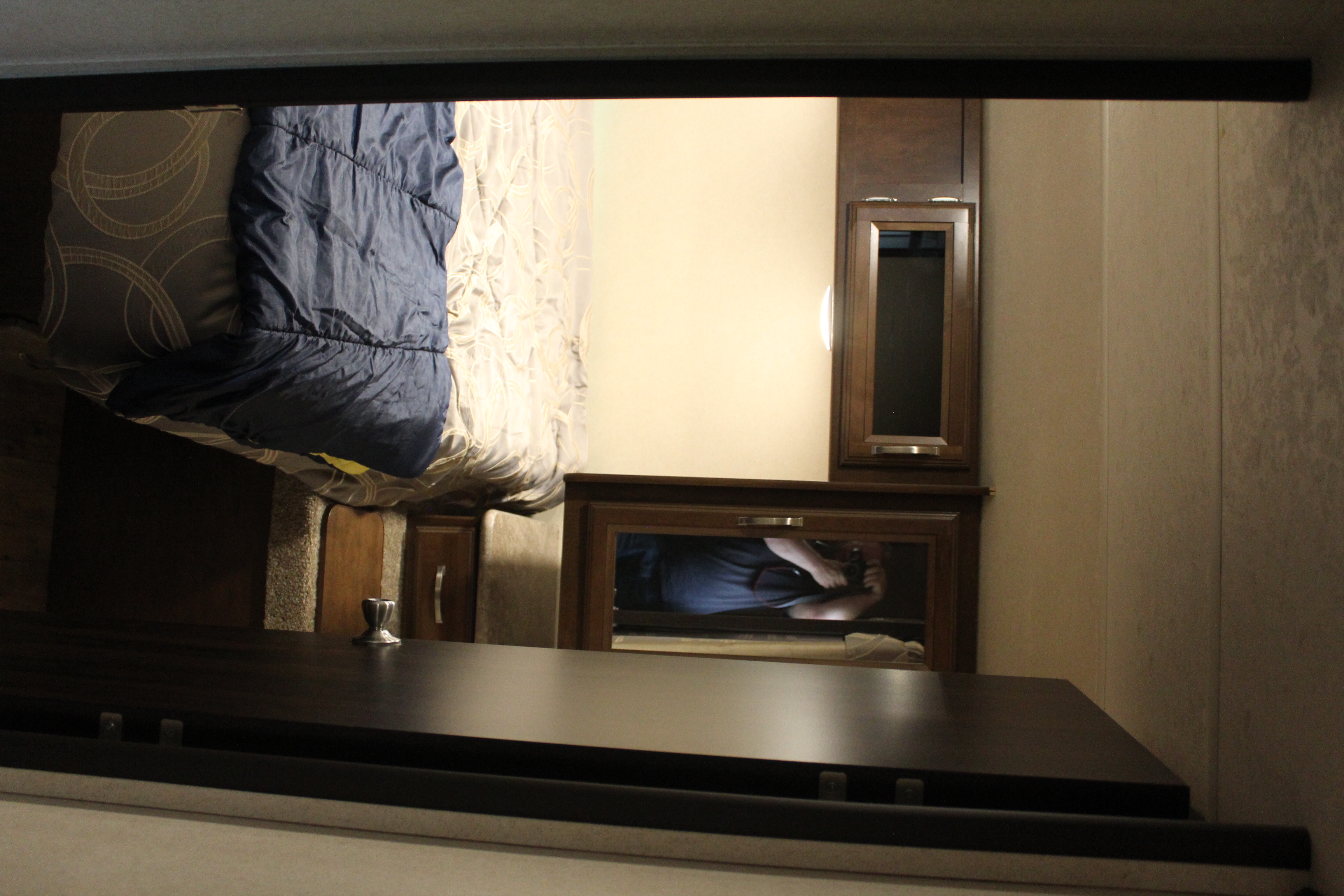 RV rental bedroom interior, featuring a bed with blue comforter, wood cabinetry, and a mirror reflecting the photographer.. Forest River Salem Hemisphere Hyper-Lyte 2017