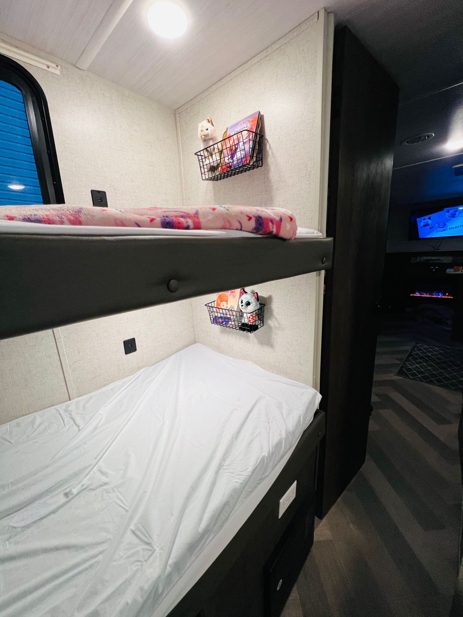 Cozy RV rental bunk beds featuring convenient charging ports, bedside storage baskets, and comfy bedding in a light interior.. Forest River Wildwood X-Lite 2020