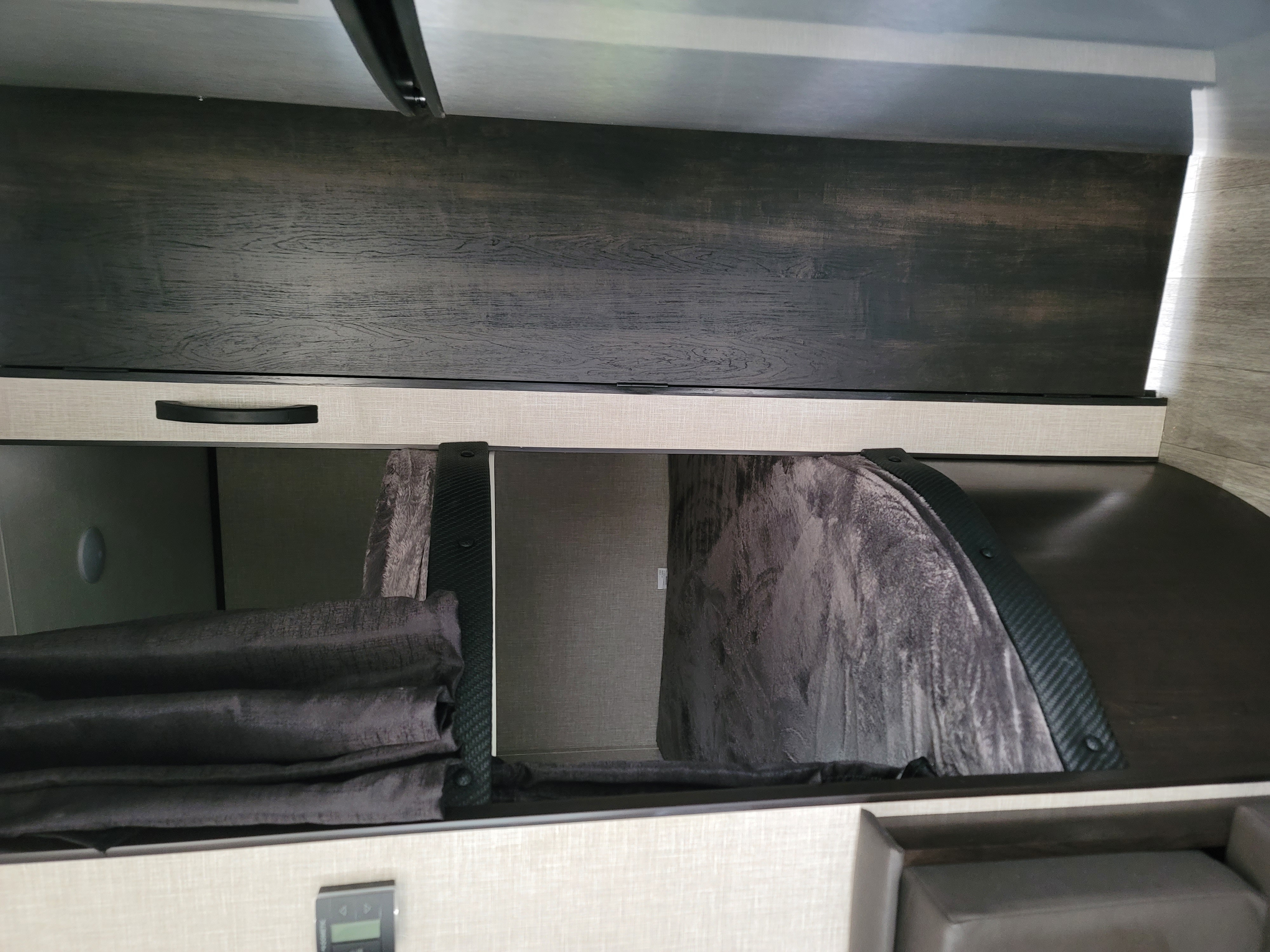 Spacious overhead bunk in an RV rental, with a dark privacy curtain and cozy bedding. An ideal sleeping/storage solution.. Jayco Jay Flight SLX 2022