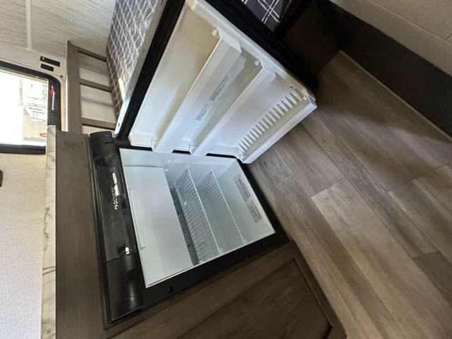 RV rental interior: A compact Dometic fridge/freezer, with open doors, integrated below a bunk bed. Functional living space.. Viking Saga 16SFB 2022