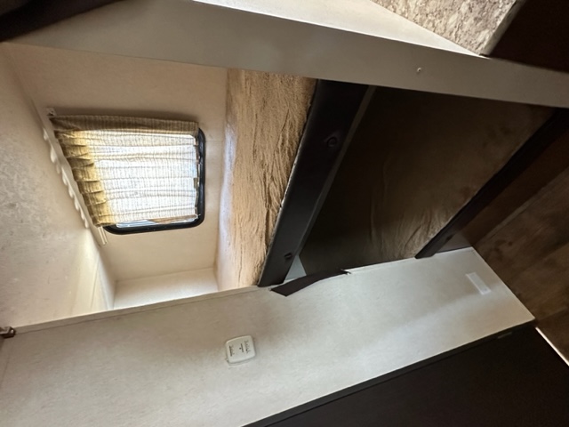 View inside an RV rental showing a bunk bed, window with blinds, and control panel on the light-colored wall.. Wildwood X-Lite 230BHXL 2018