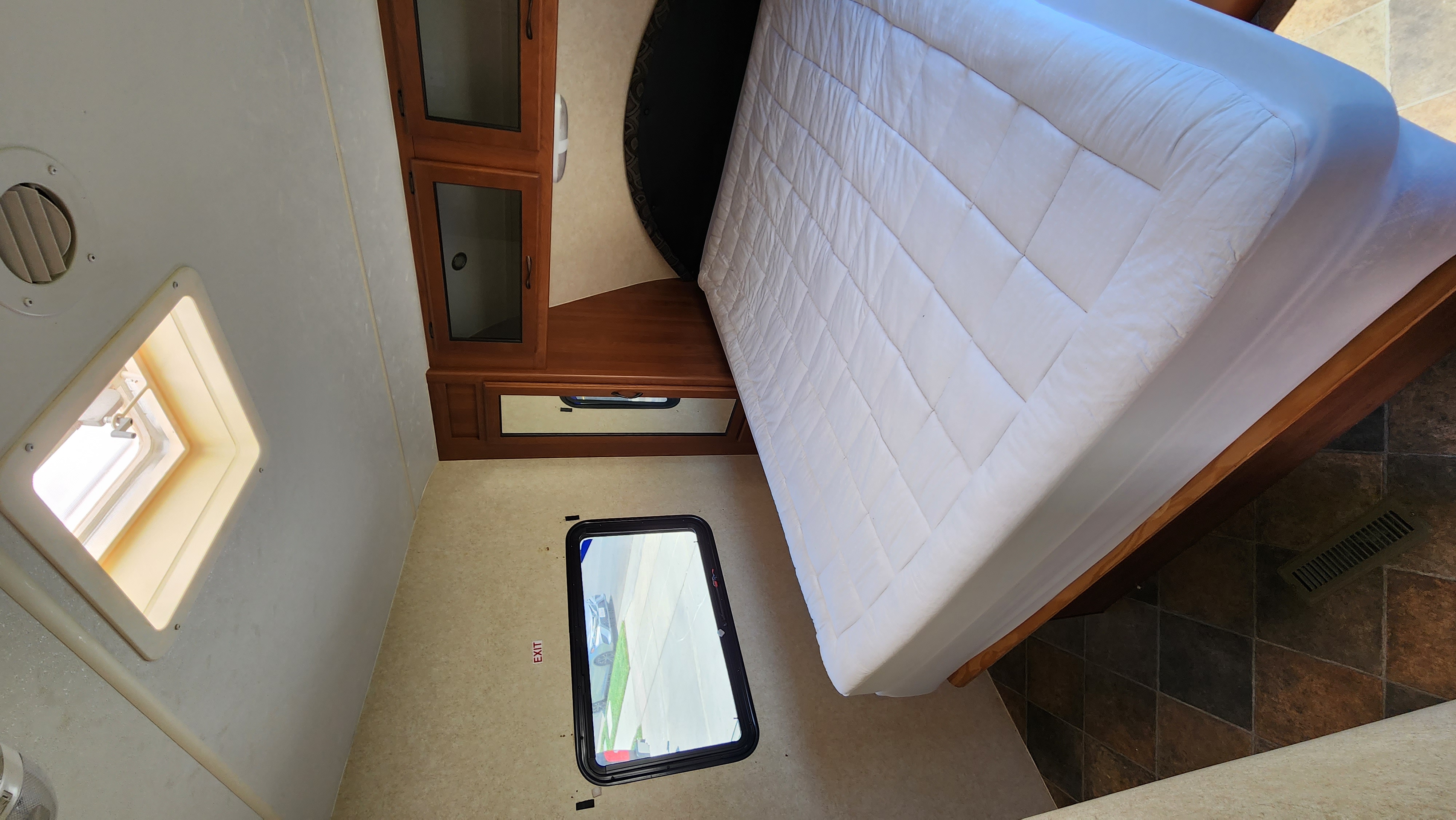 Compact RV rental bedroom with comfy bed, emergency exit window, and wooden storage. Ready for your adventure!. Pacific Coachworks Powerlite 2014