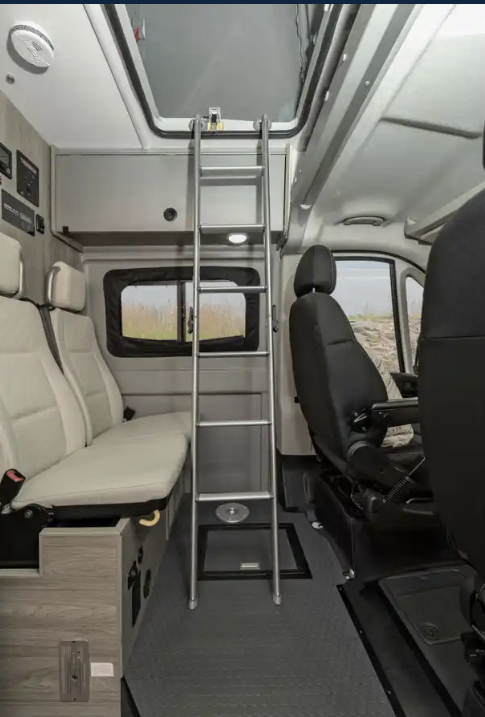 Spacious RV rental interior featuring flexible seating, an overhead bunk bed via ladder, and front cabin area for travel.. Winnebago Solis 2022