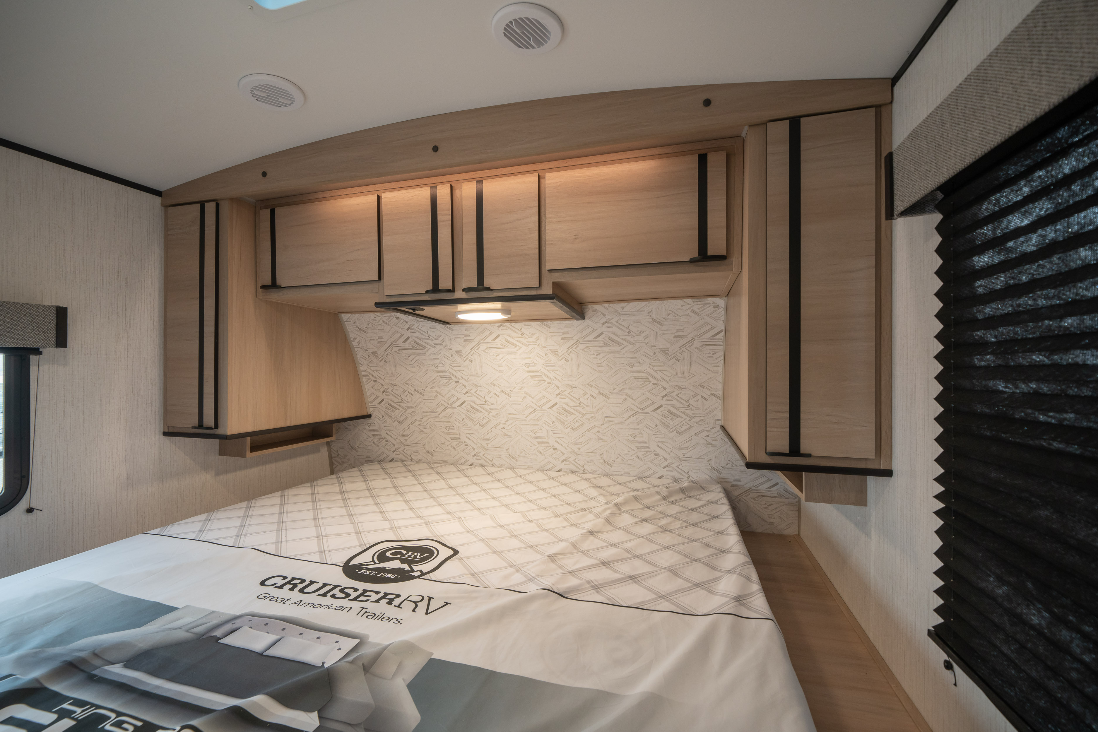 Cozy RV rental bedroom with light wood cabinetry, textured headboard, and a comfortable bed for travel.. Cruiser Rv Corp Radiance 2022